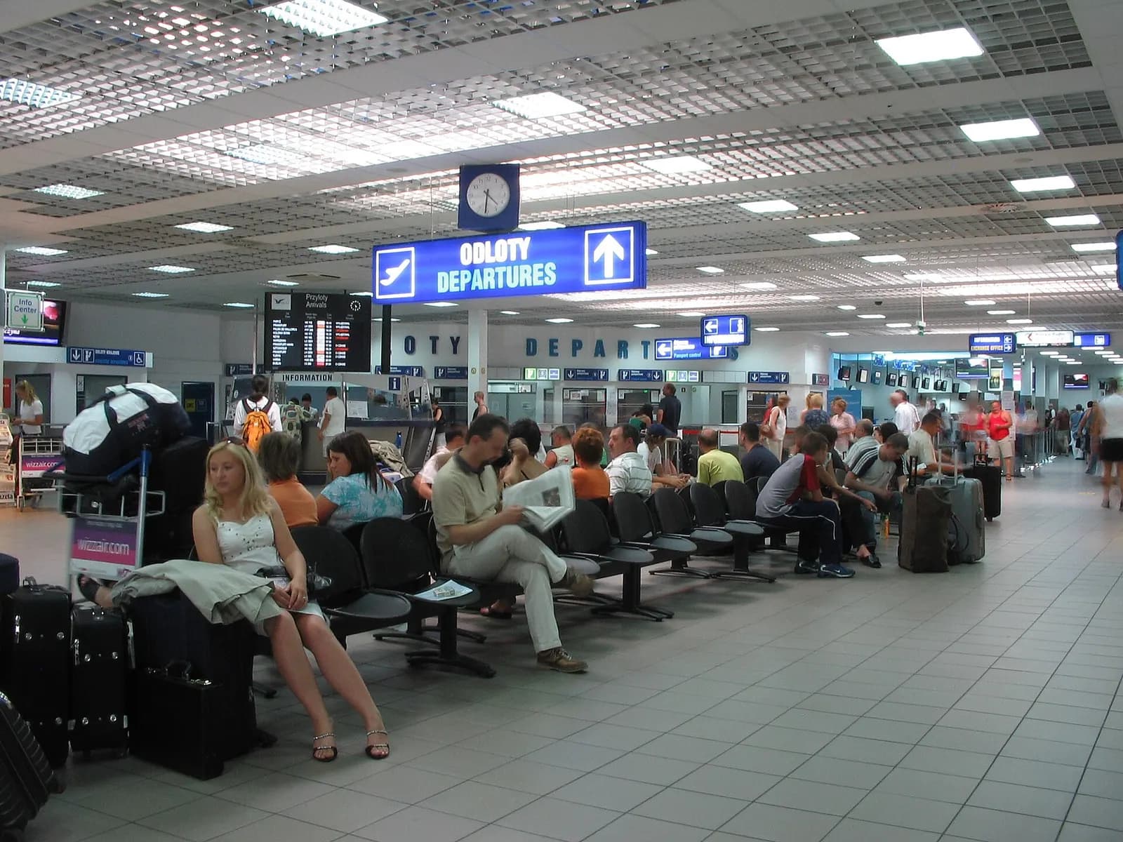 The departure waiting area in Terminal A with passenger seating in the foreground and check-in counters visible deeper in the hall.