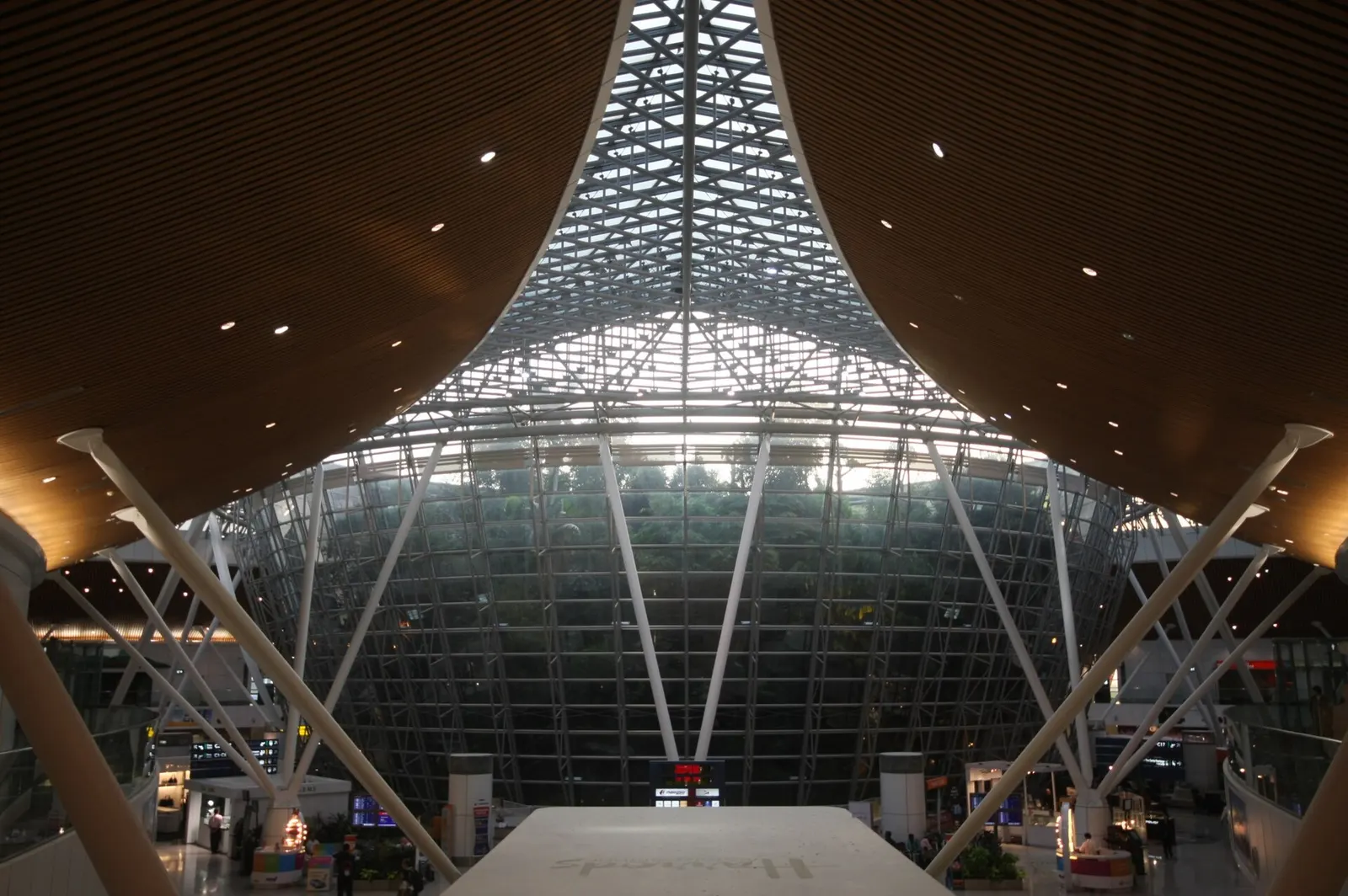 Tall palm trees and tropical greenery fill the open central garden inside the Satellite Terminal concourse.