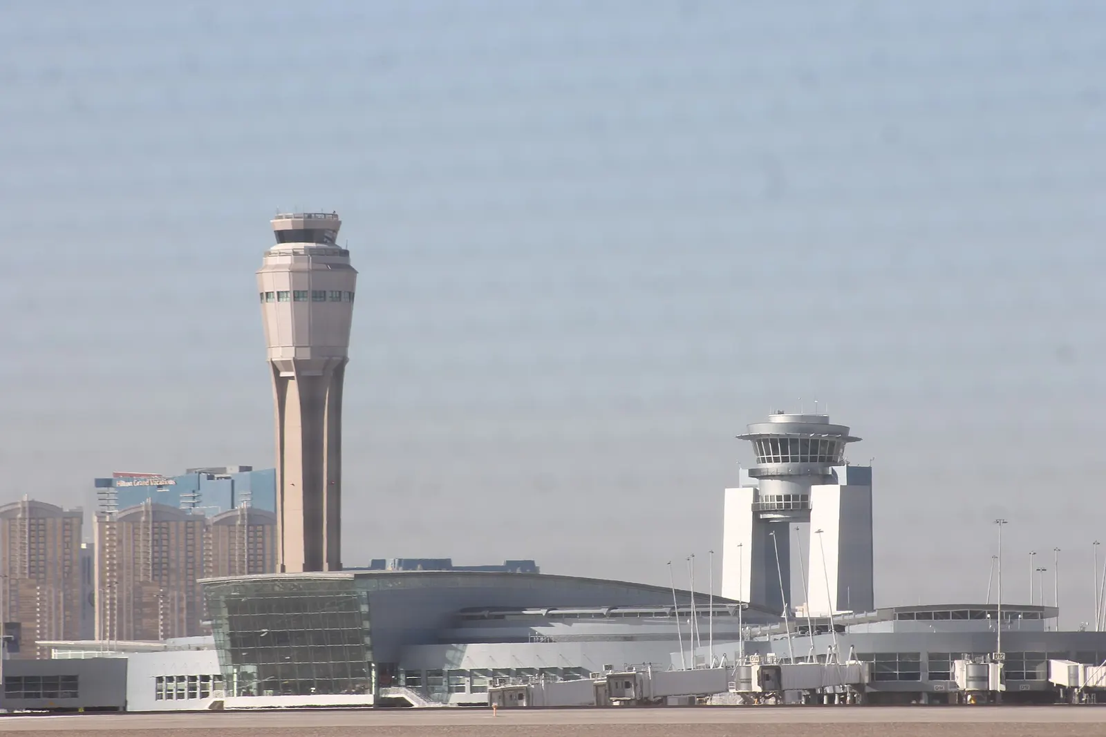 The airport's air traffic control tower and adjacent public viewing tower against a blue Nevada sky.
