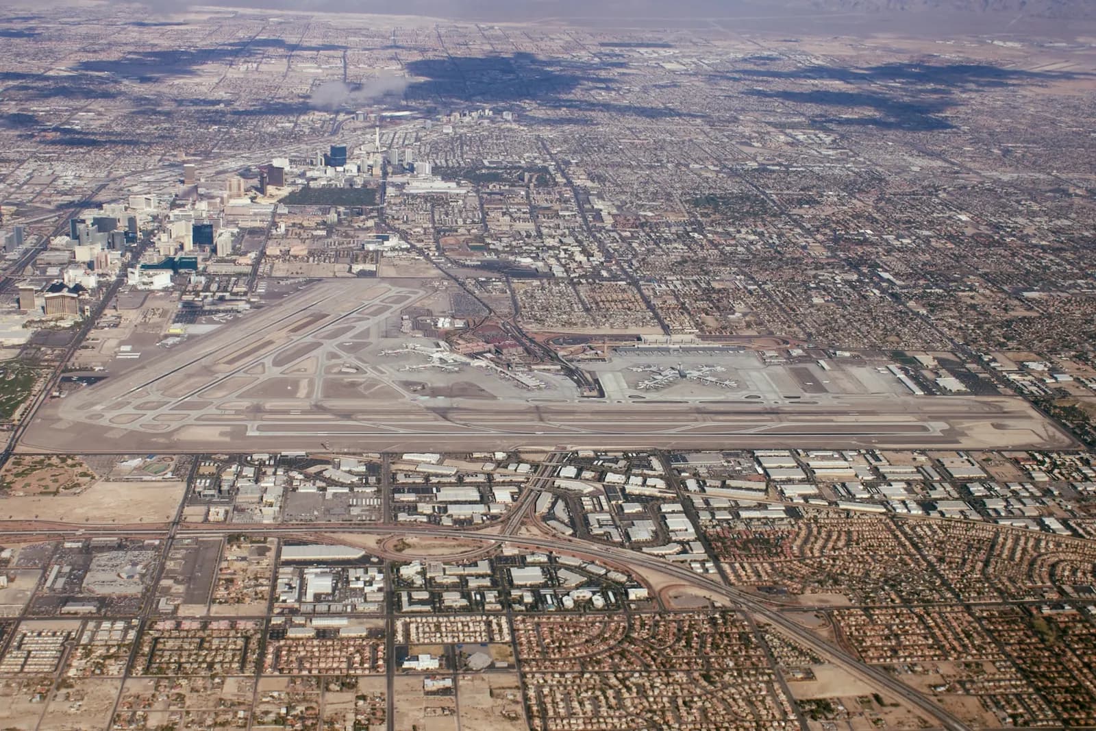 Aerial view looking north over Harry Reid International Airport runways, terminals, and surrounding desert on a clear day.