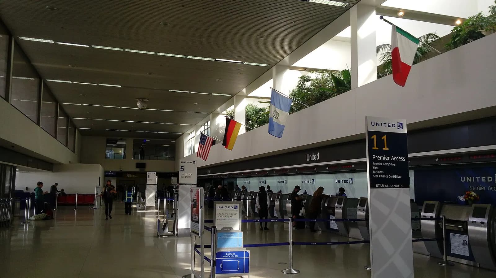 The United Airlines check-in counters in Terminal 7, with ticket kiosks, queue stanchions, and the terminal's open concourse ceiling.