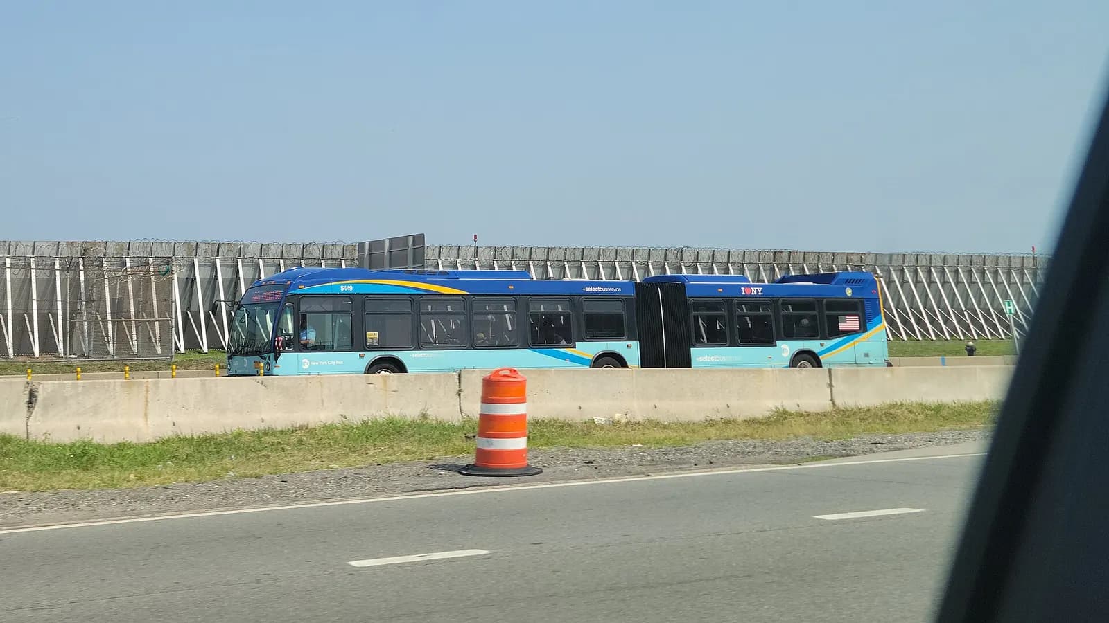 A West Side–Broadway-106th Street-bound M60 SBS bus traveling west on Runway Drive through the west end of LaGuardia Airport, looking from the Grand Central Parkway east of 82nd Street in East Elmhurst, Queens. The M60 route technically terminates at Terminal C; this bus will head north to the Marin