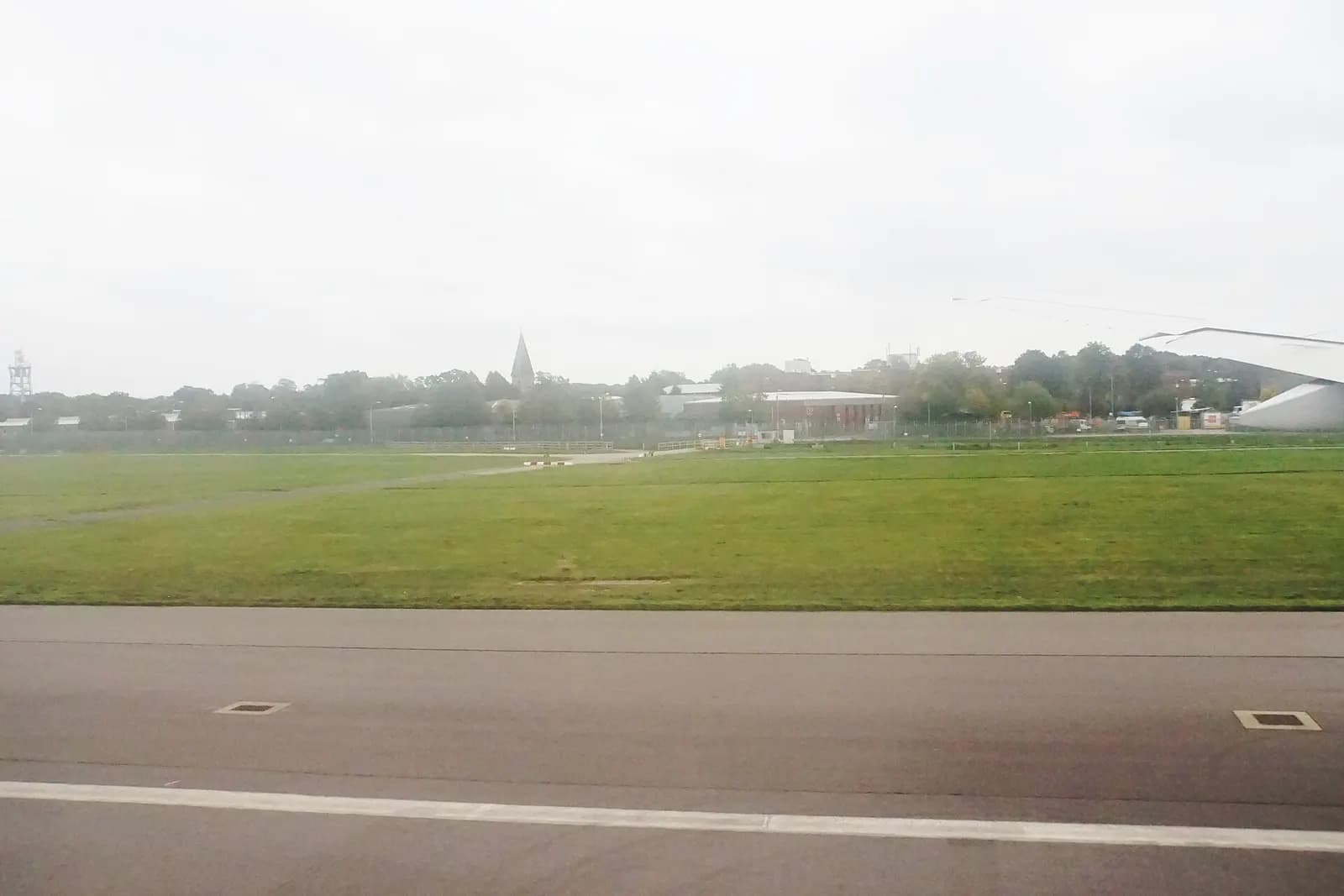 A broad view of the southern side of London Gatwick Airport with terminal buildings, airfield, and open countryside beyond.