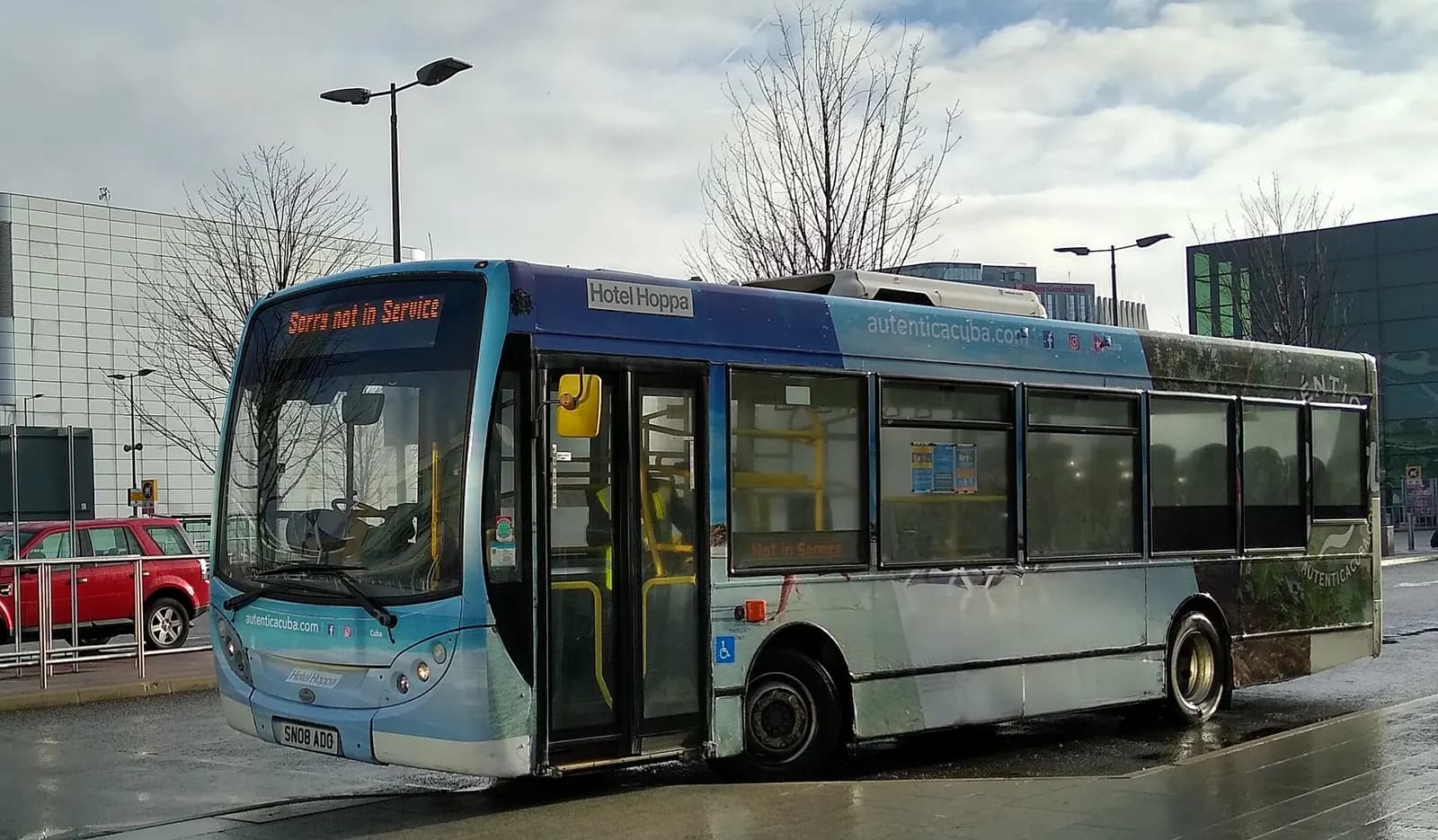 A Hotel Hoppa shuttle bus parked outside Heathrow Terminal 3 after dropping off passengers at the curb.