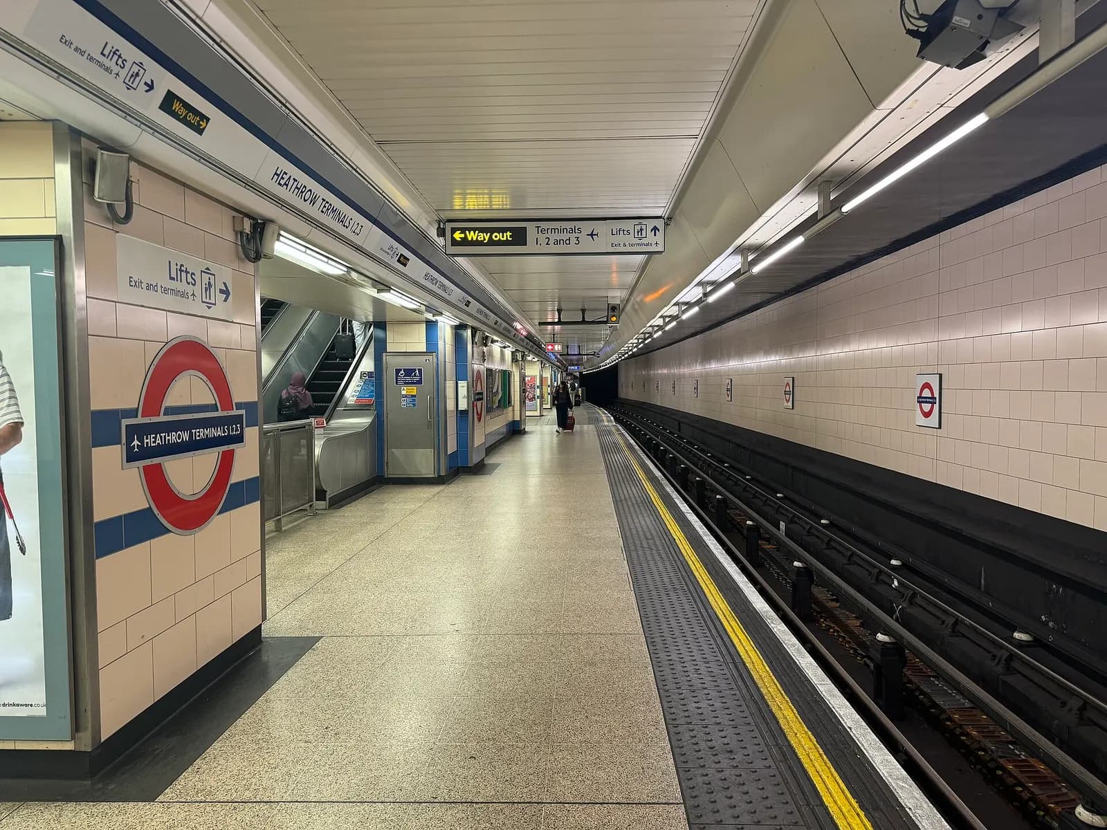 The northbound platform at Heathrow Terminals 1, 2 and 3 station with Piccadilly line signage, tracks, and a train waiting at the platform.