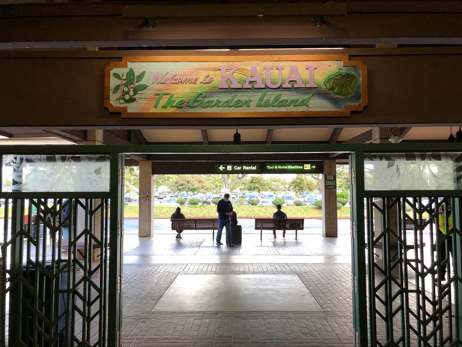 Welcome to Kauai sign over the terminal exit, with car-rental, taxi, hotel-shuttle, and rideshare wayfinding