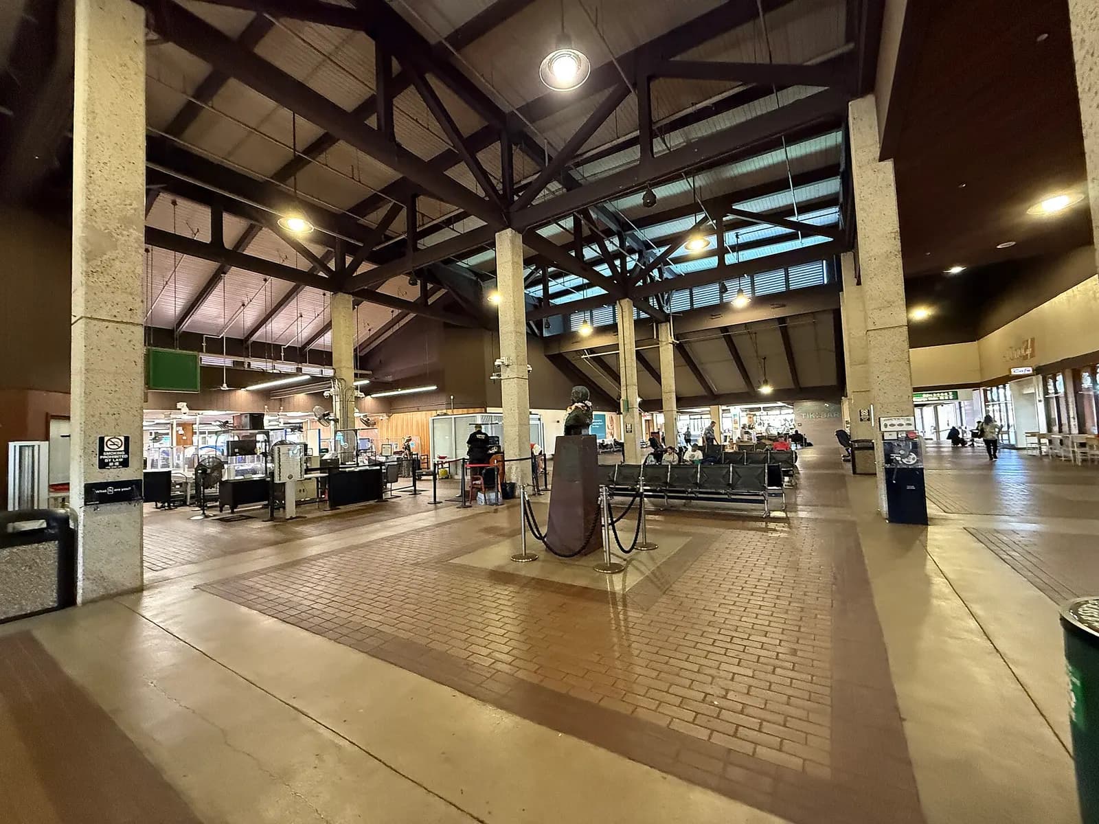 Landside public hall at Lihue Airport with the high timber roof and a bust on a pedestal