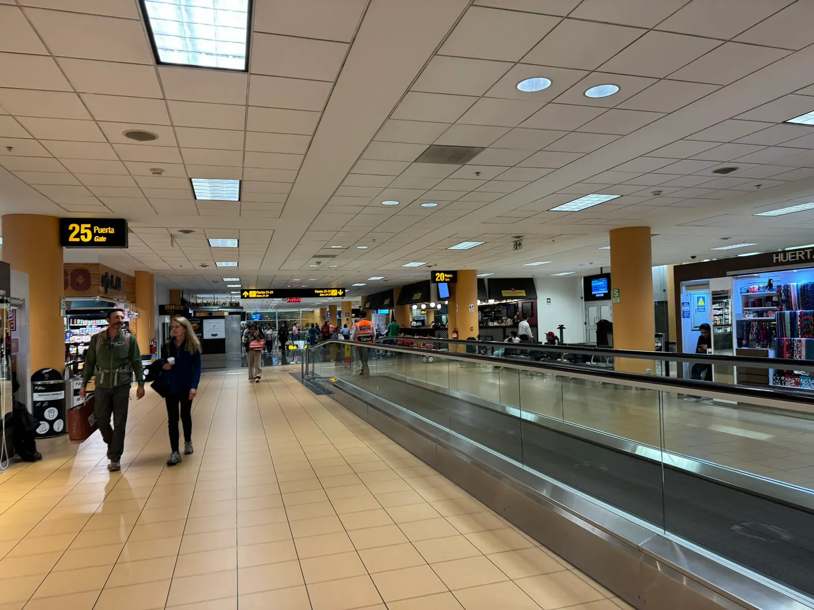 The international departures concourse with gate seating, flight information screens, and travelers waiting near boarding areas.