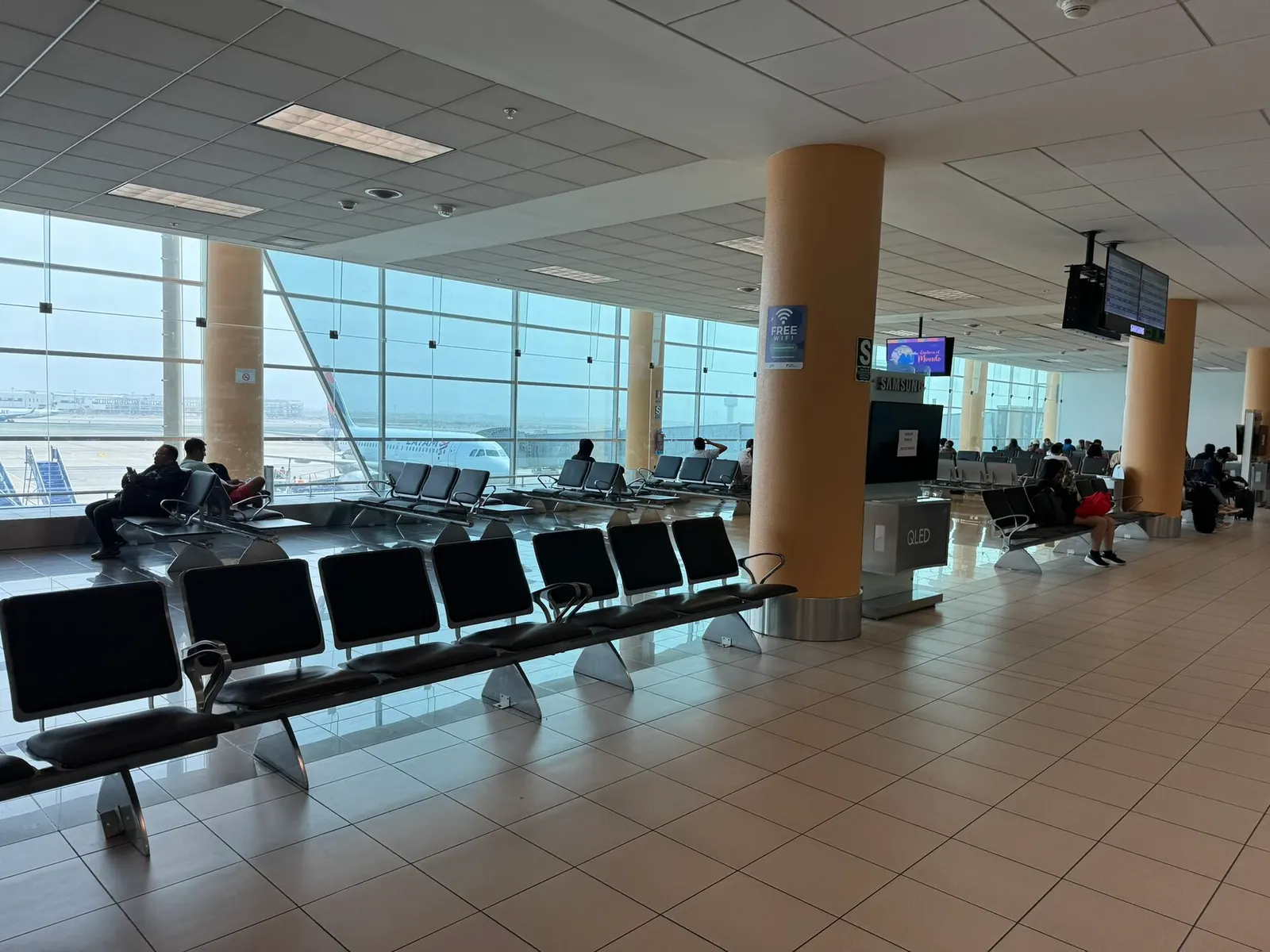 National domestic boarding gates with seating rows, gate number signs, and passengers waiting to board.
