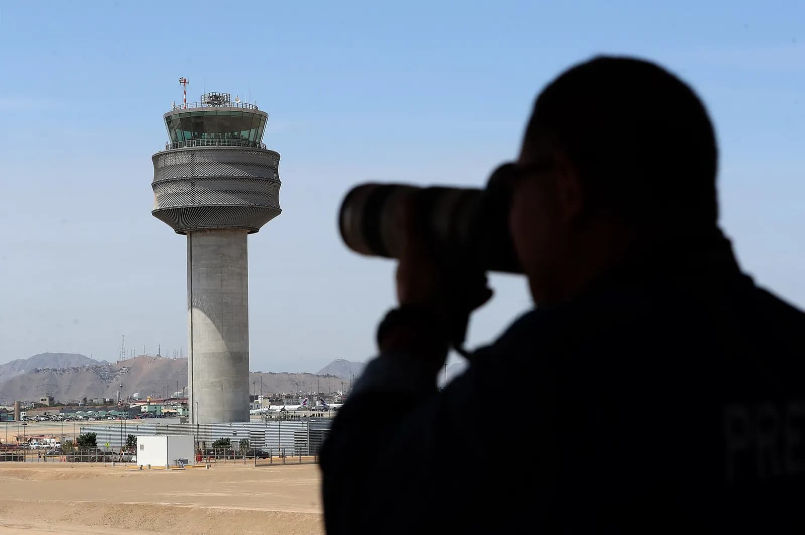 The airport control tower and a newly opened runway with officials gathered for an inauguration ceremony on the airfield.