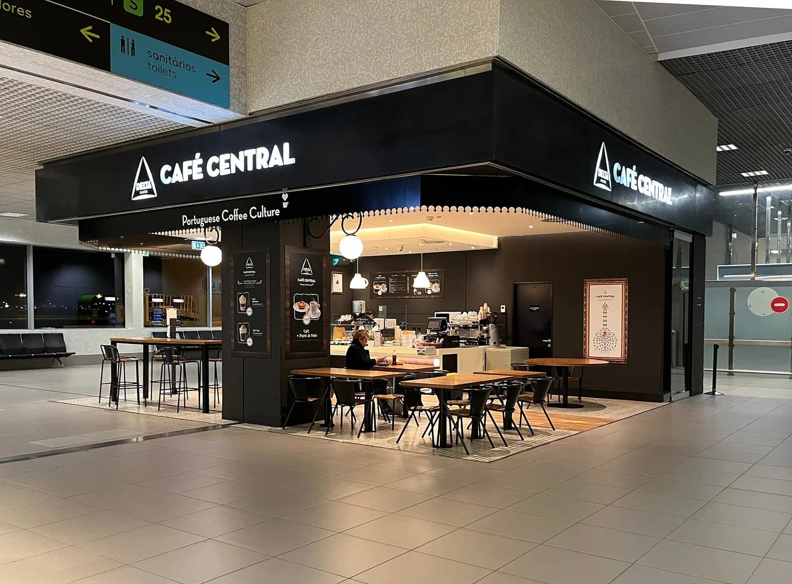 The Café Central restaurant interior with tables, counter service, and airport passengers dining.