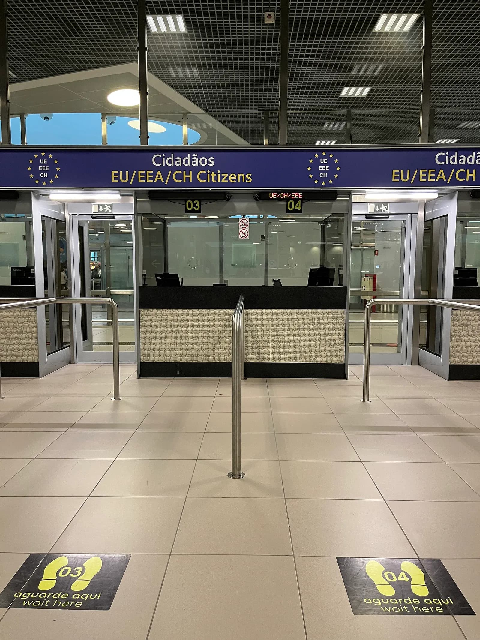 Passengers lined up at passport control booths staffed by border officers in the arrivals hall.