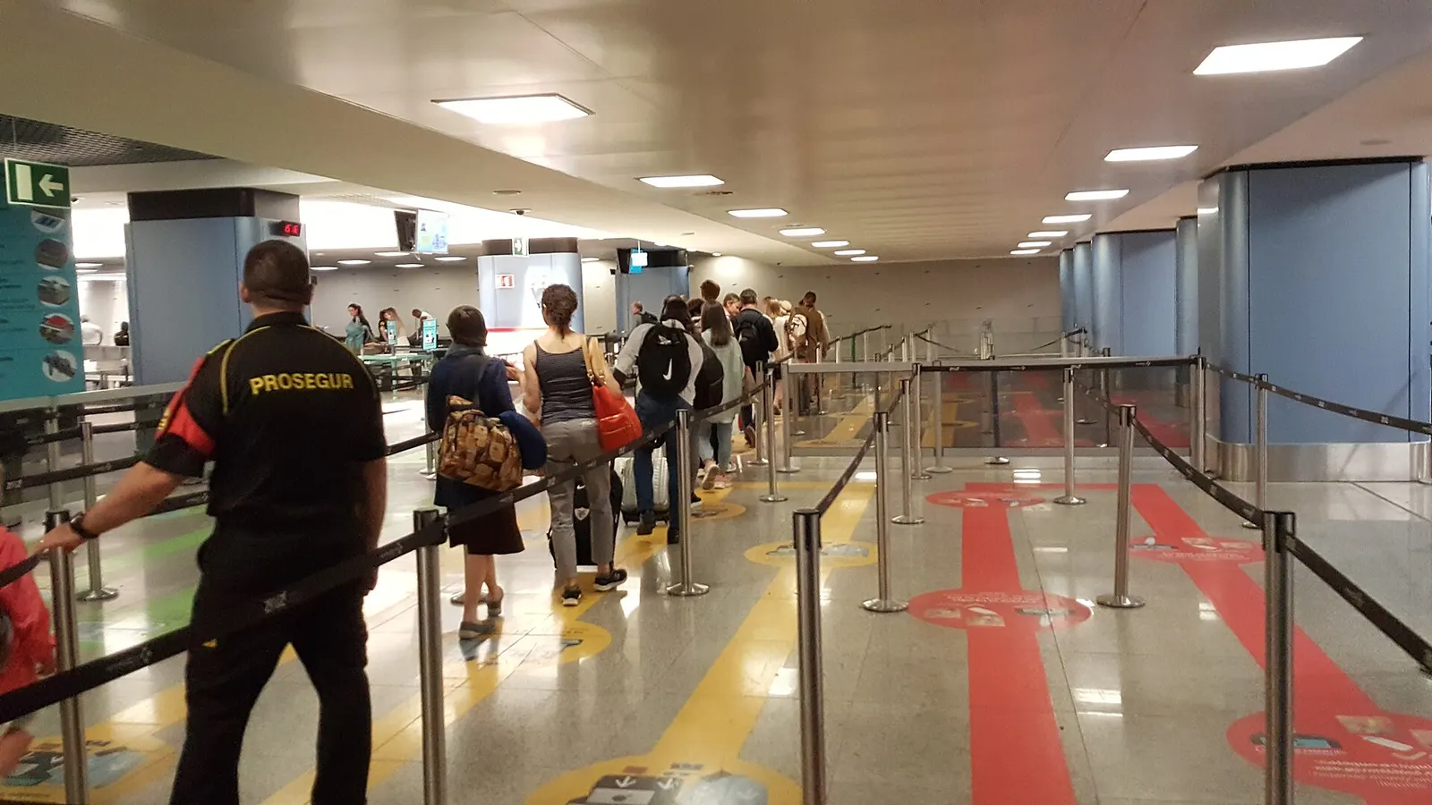 A long queue of travelers waiting in a cordoned corridor before the security screening gates.