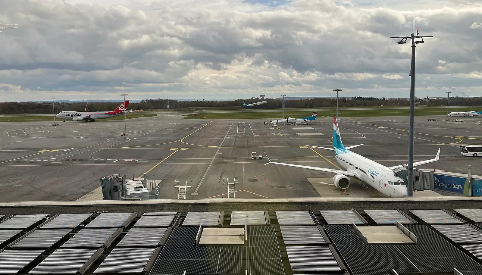 Het platform van de luchthaven Findel te Luxemburg. Met vliegtuigen van Luxair (Boeing 737; De Havilland Canada Dash 8-400), Cargolux (Boeing 747) en Air Dolomiti (Embraer 190 of 195).