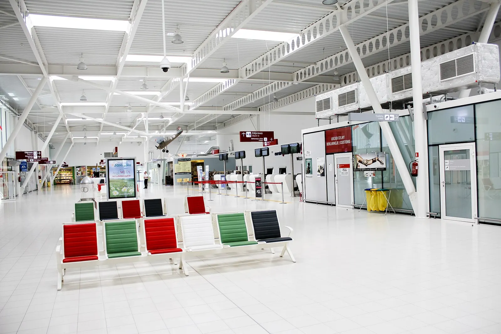 Lublin Airport landside hall with check-in, customs desk and hanging historic aircraft