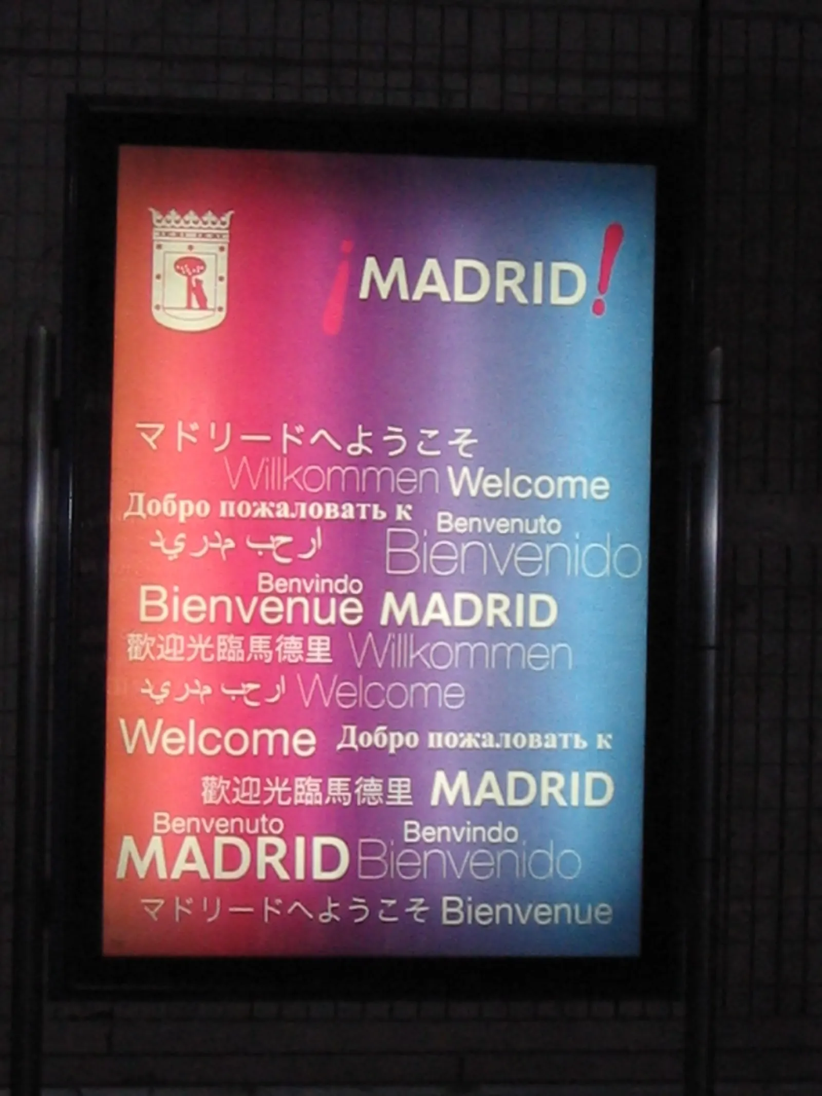 A multilingual welcome sign reading "Bienvenido / Welcome" to Madrid at the airport, displayed in several languages.