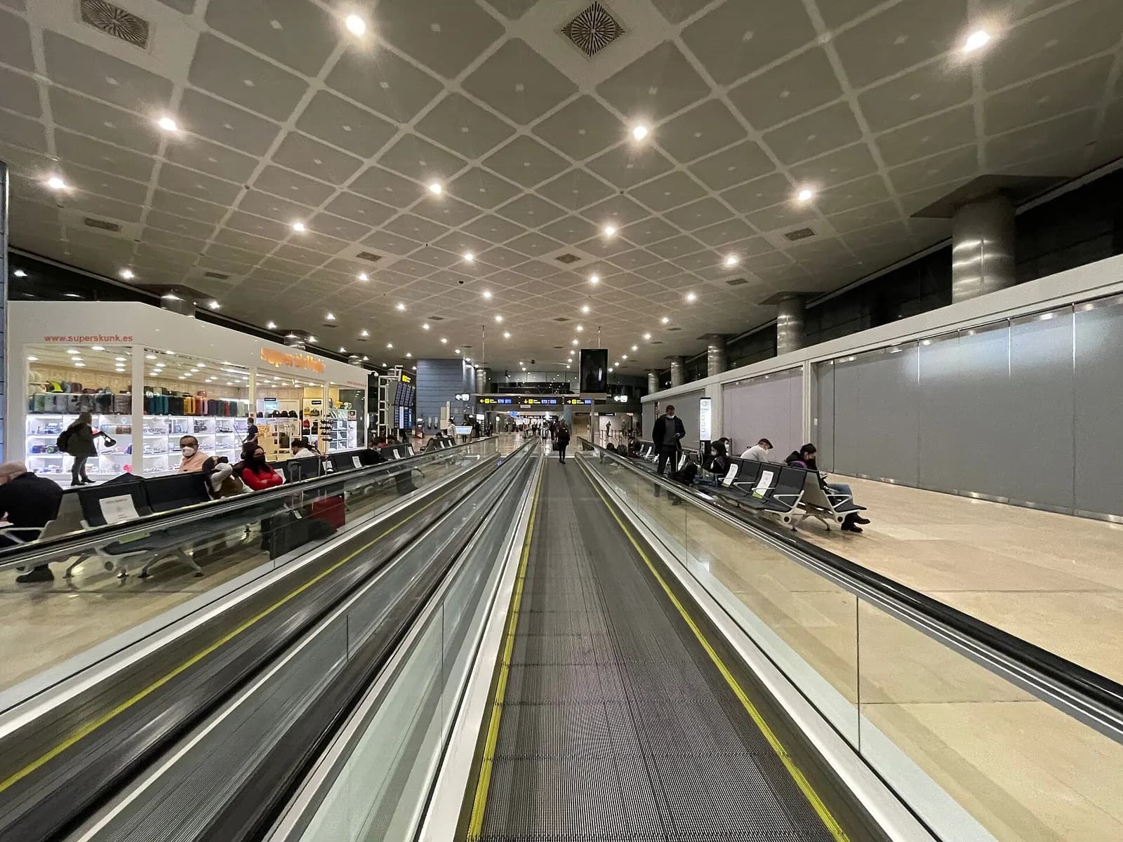A gate hold room in Terminal 3 with rows of seats, flight information displays, and large windows overlooking the apron.