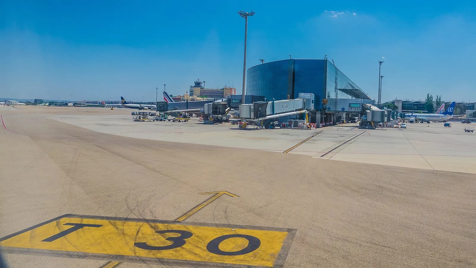 The airside concourse of Terminal 3 with gate seating areas, shopfronts, and a high ceiling lined with skylights.
