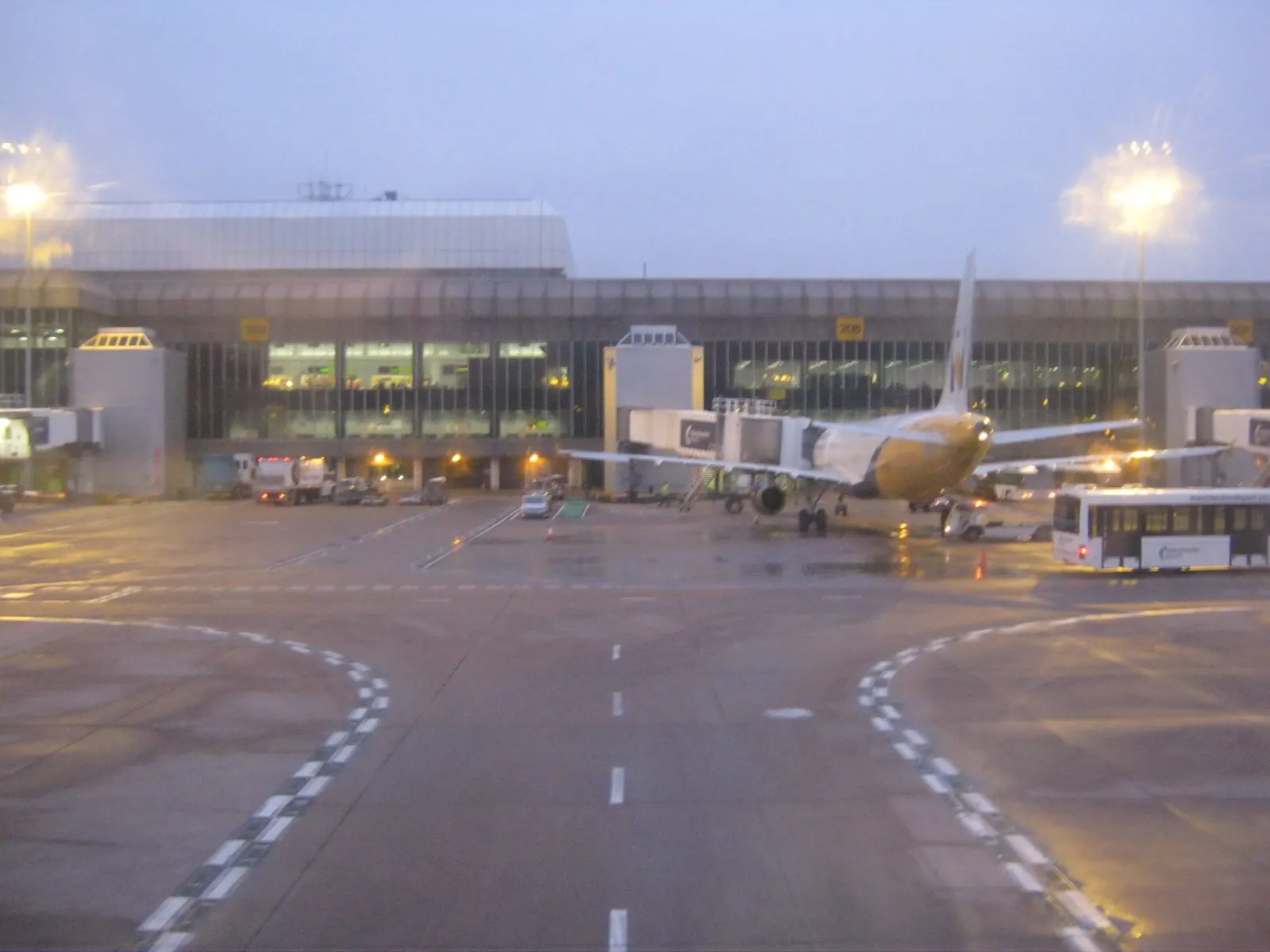 Rear exterior of Manchester Airport Terminal 2 showing the building facade, service roads, and airside perimeter.