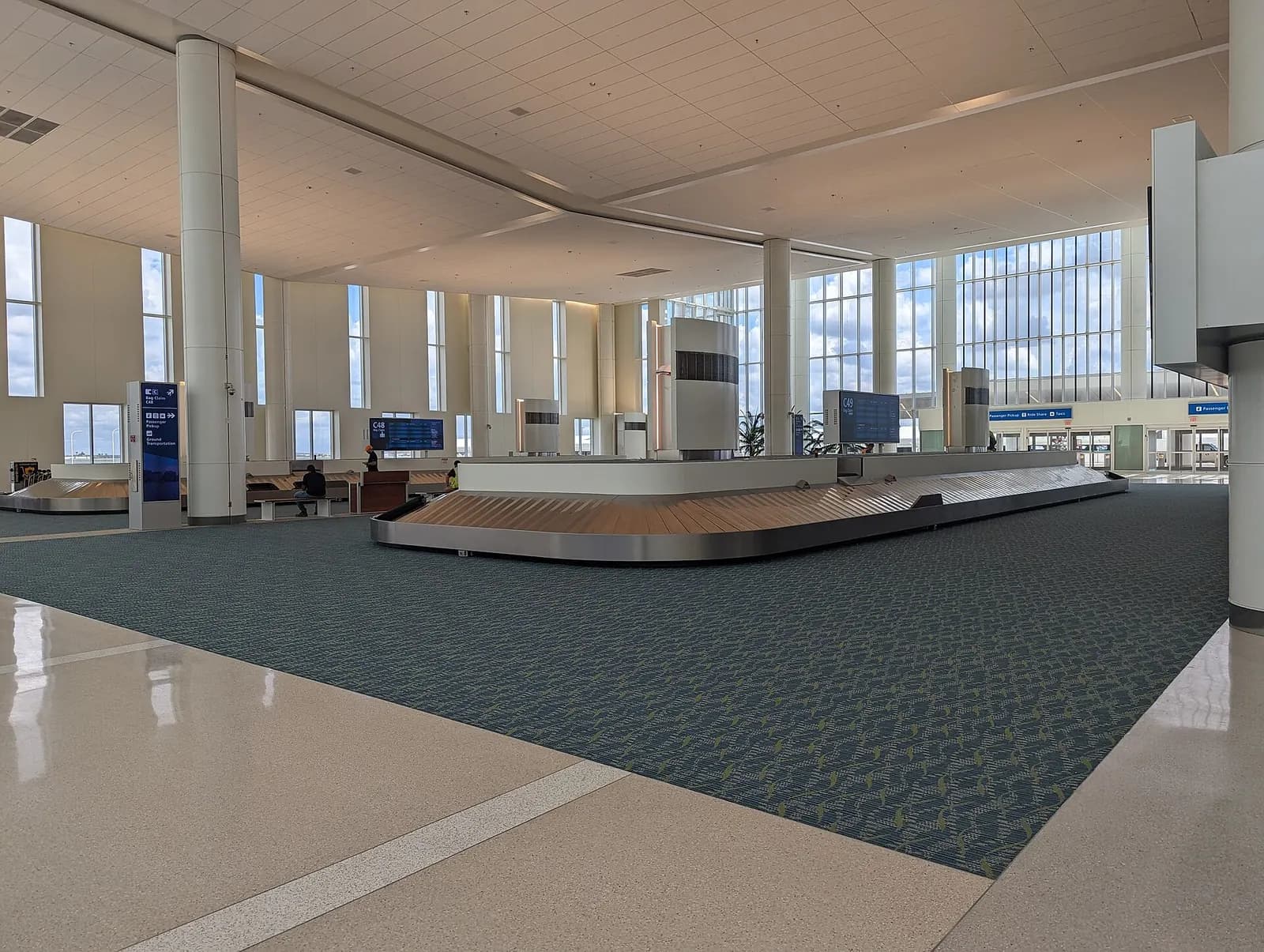 The baggage claim hall in Terminal C at Orlando International Airport with multiple carousels, flight-information displays, and arriving passengers.