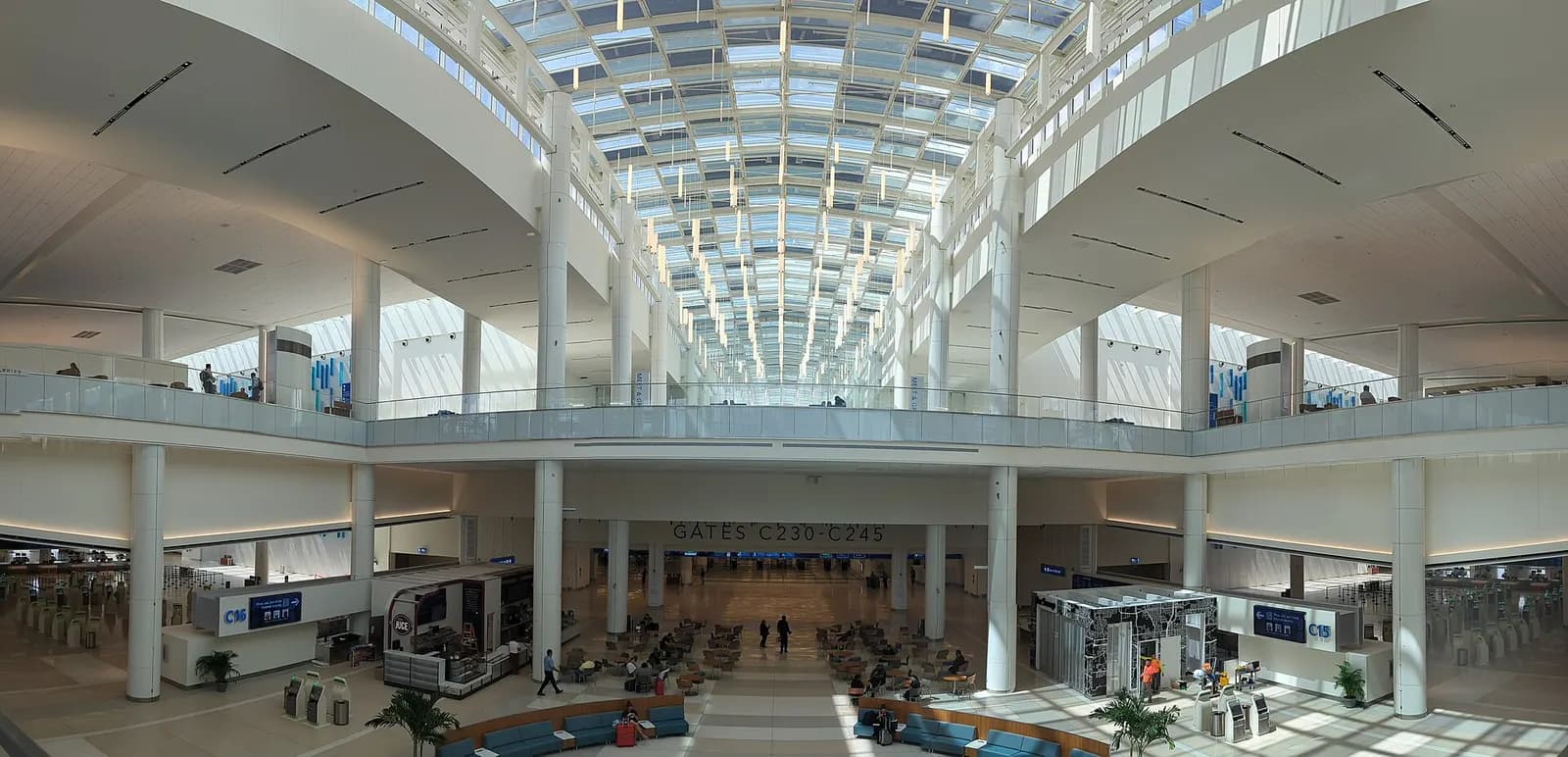 The bright, open atrium of the new Terminal C at Orlando International Airport with modern architecture, glass walls, and travelers moving through the space.