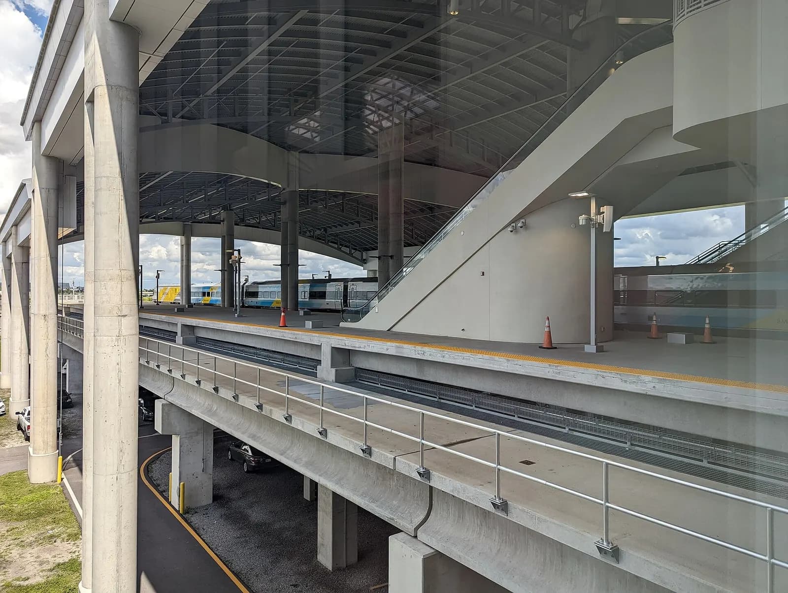 A Brightline passenger train stopped at the Orlando International Airport Intermodal Terminal platform beneath the airport.
