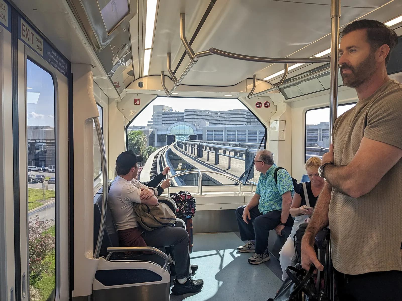 Inside an automated people mover train car at Orlando International Airport, showing rows of seats and large windows along the guideway.
