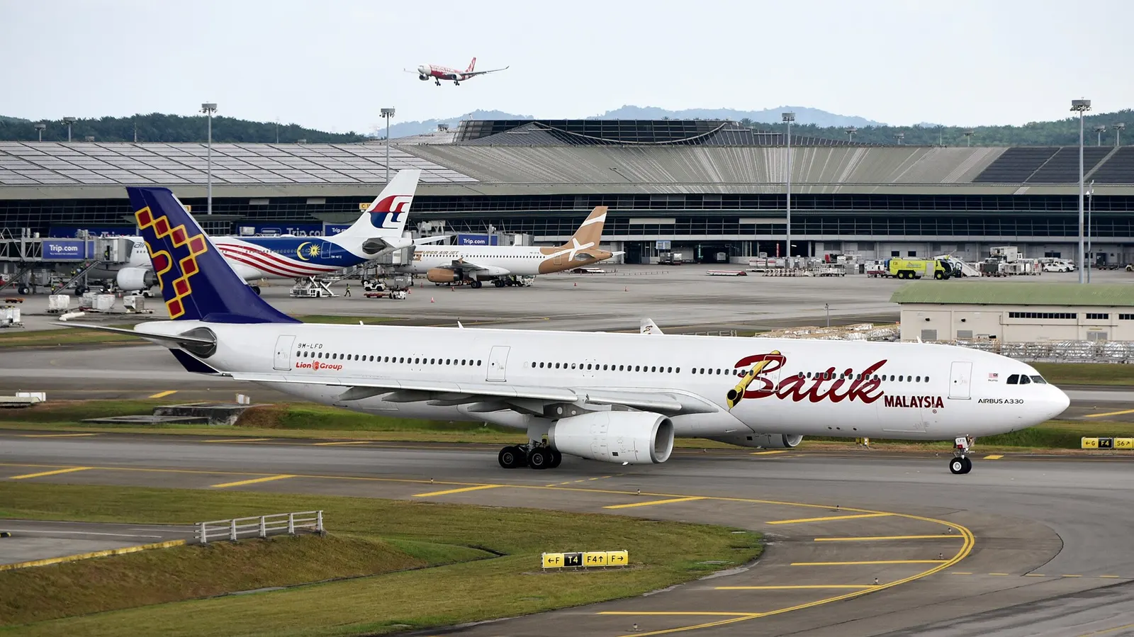 Batik Air Malaysia Airbus A330-343X 9M-LFD taxiing at Kuala Lumpur International Airport (KUL/WMKK), near Kuala Lumpur, Malaysia, on departure for Melbourne Airport (MEL/YMML) as OD175 – in the background, AirAsia X Airbus A330-343 9M-XXW is approaching runway 32R on arrival from Kansai Internationa