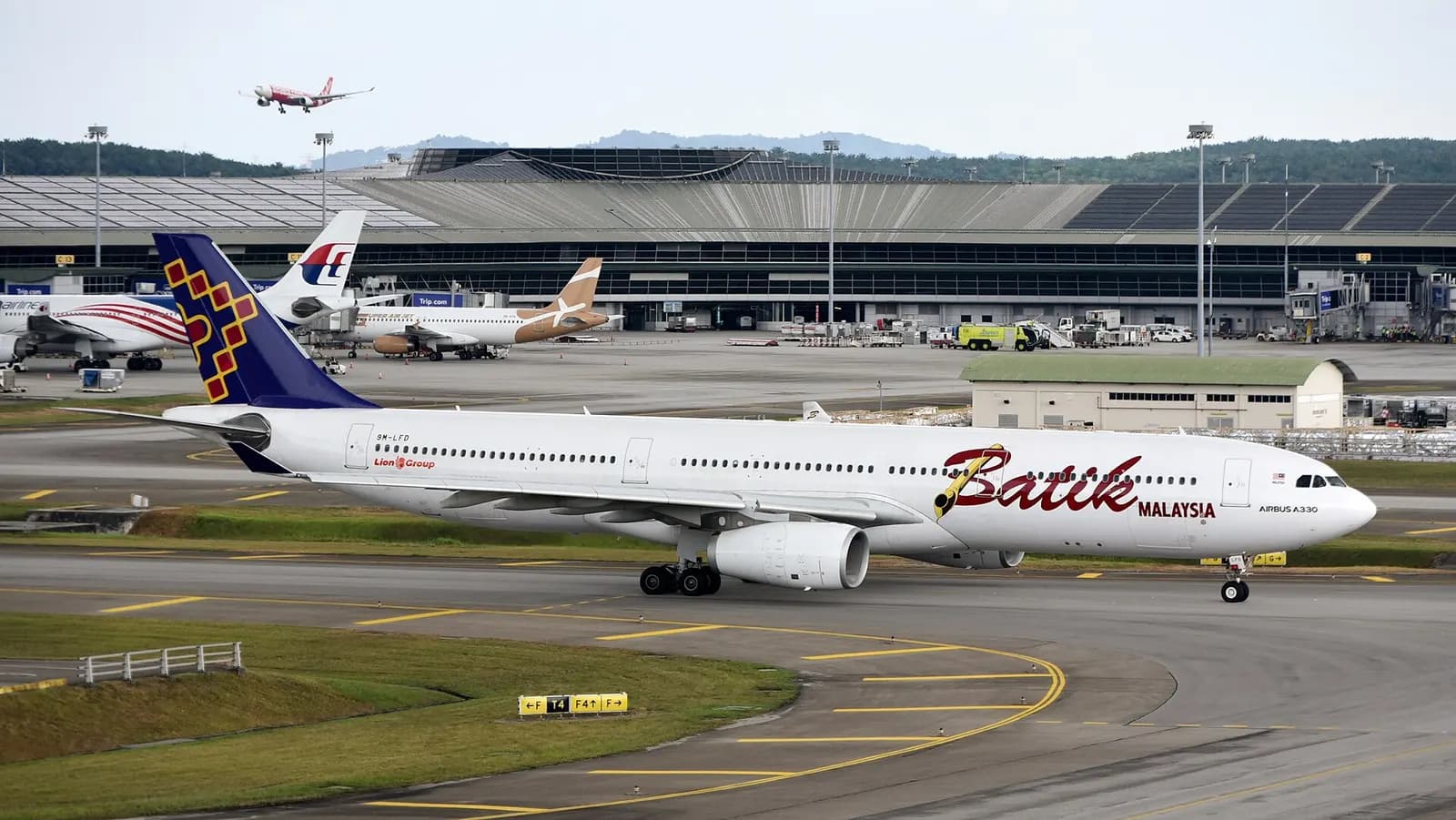 Batik Air Malaysia Airbus A330-343X 9M-LFD taxiing at Kuala Lumpur International Airport (KUL/WMKK), near Kuala Lumpur, Malaysia, on departure for Melbourne Airport (MEL/YMML) as OD175 – in the background, AirAsia X Airbus A330-343 9M-XXW is approaching runway 32R on arrival from Kansai Internationa