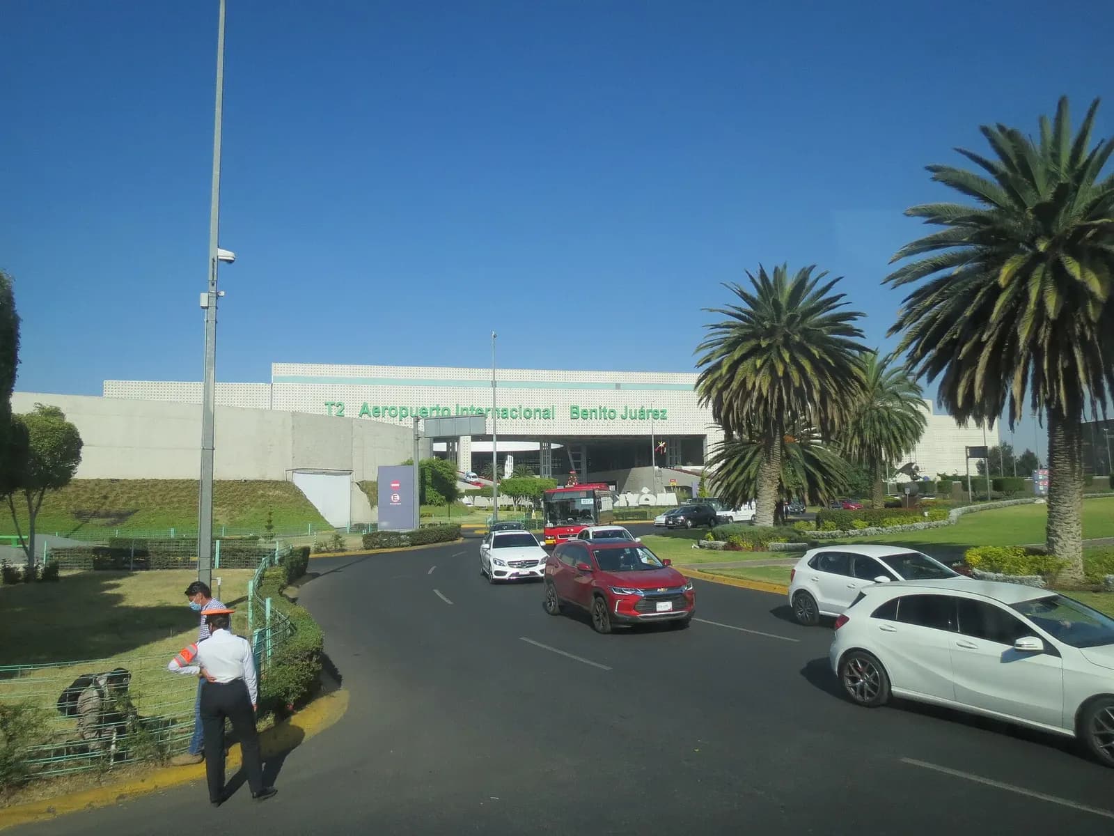 Exterior of Terminal 2 at Mexico City International Airport, with its modern glass-and-steel architecture and drop-off road in front.