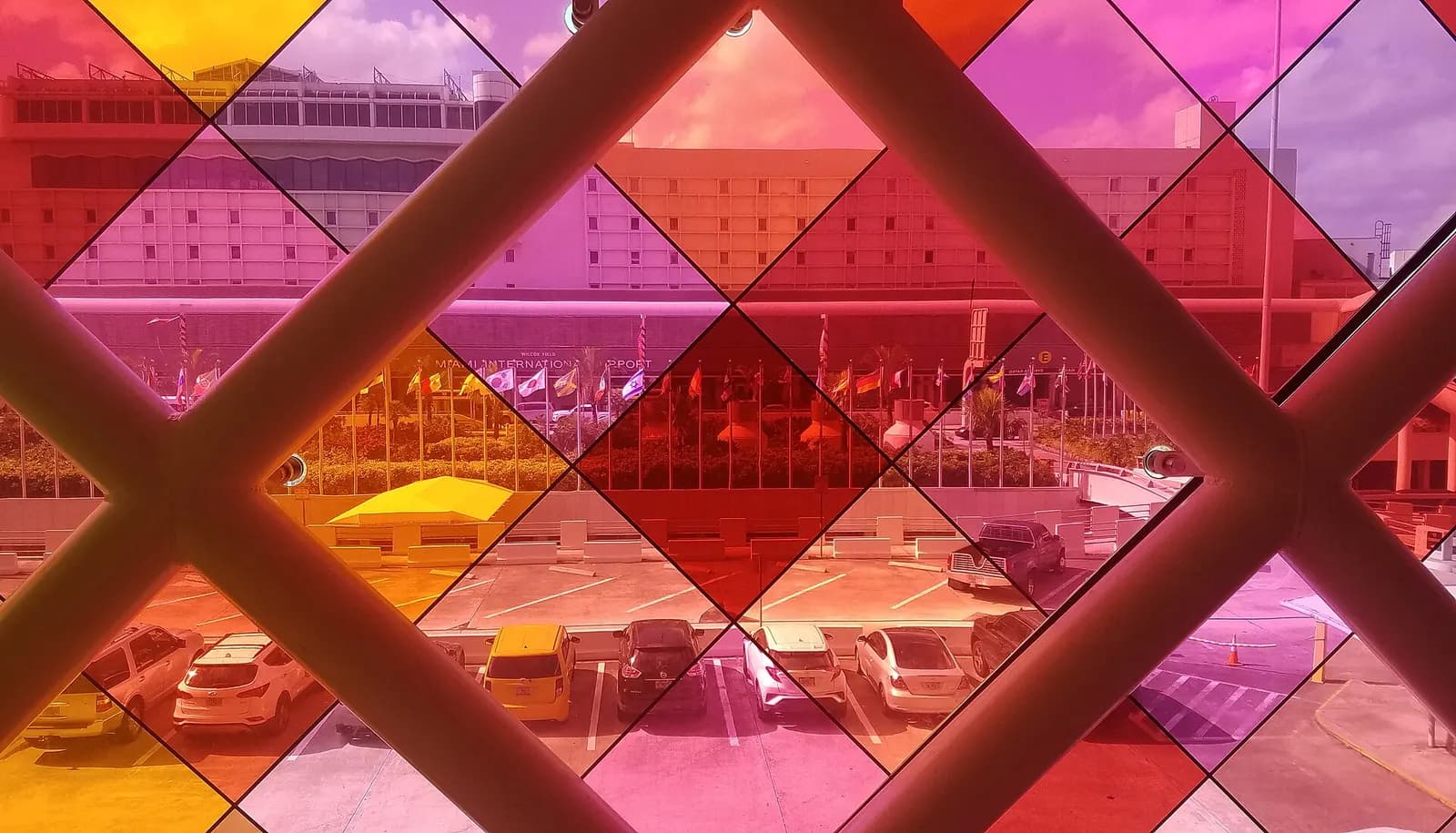 A terminal interior at MIA seen through colorful stained-glass-style window panels that cast multicolored light.