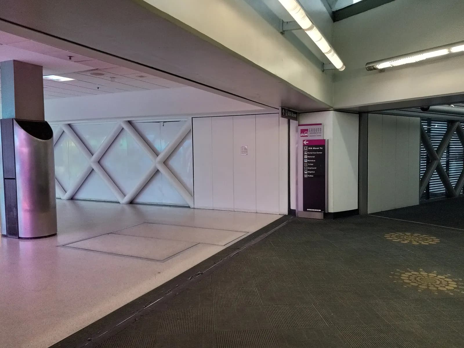 A spacious, brightly lit departure hall at Miami International Airport with check-in areas and the Dolphin Garage visible beyond the terminal windows.