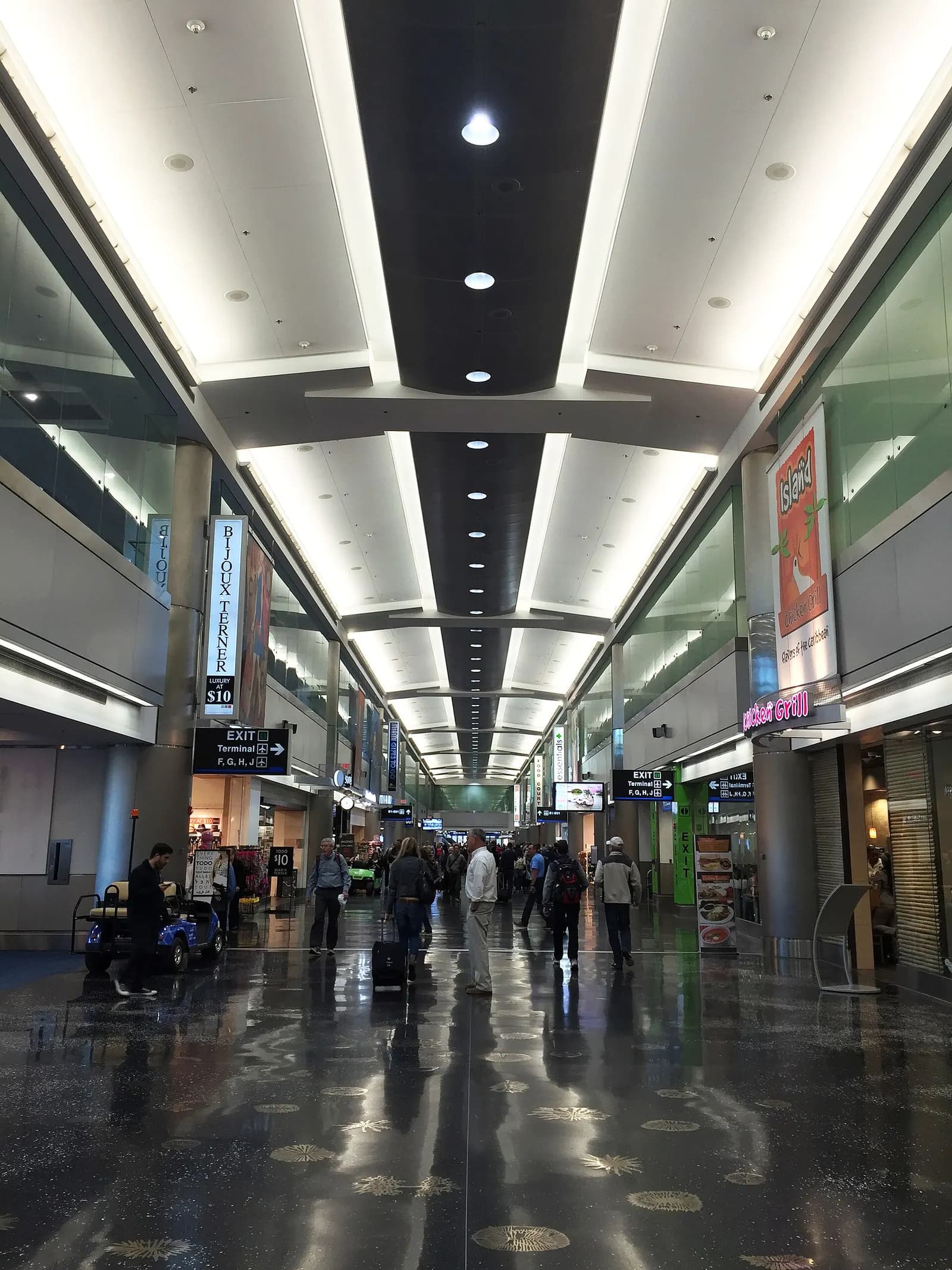 The interior of Concourse D at MIA, with a long gate corridor, seating areas, and flight information displays along the walls.
