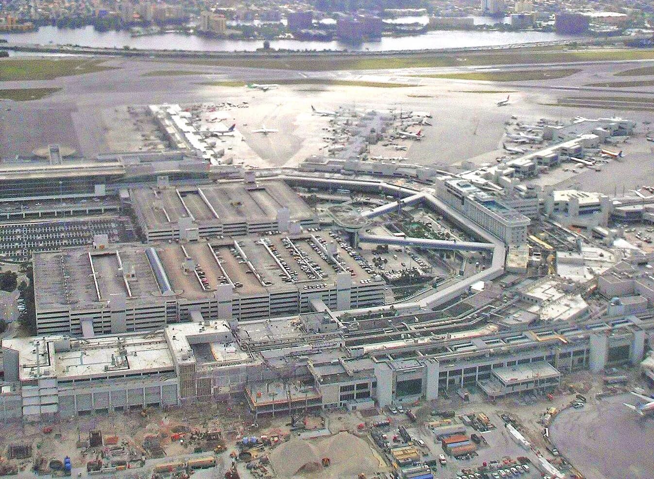 An aerial photograph of Miami International Airport showing multiple runways, terminal buildings, and surrounding roads and neighborhoods.