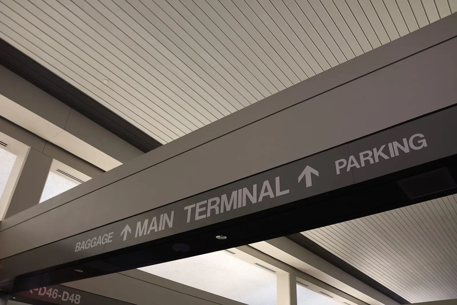 Concourse D ceiling signs for Baggage, Main Terminal, Parking, and gates D46–D48.