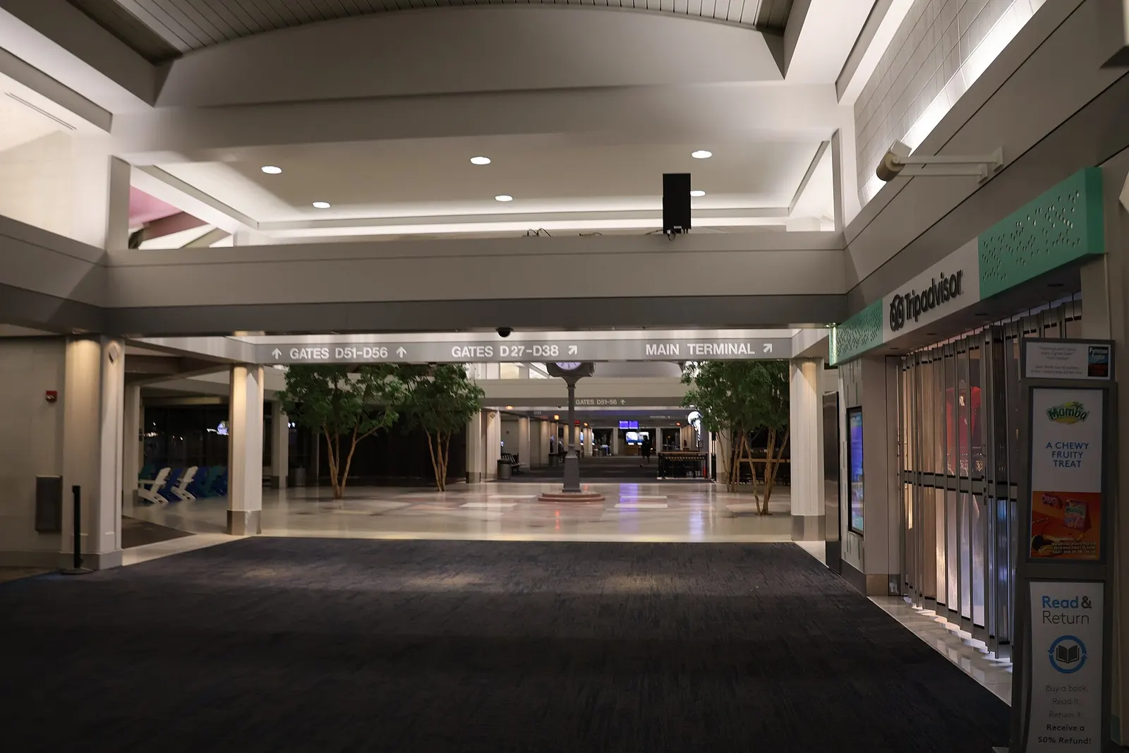 Concourse D junction with Tripadvisor shop and signs for gates D51–D56 and D27–D38.