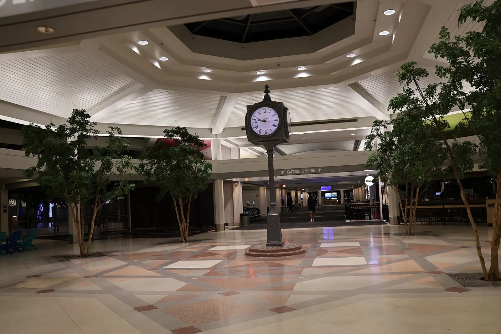 Concourse D rotunda clock under the octagonal skylight with a D51–D56 sign.