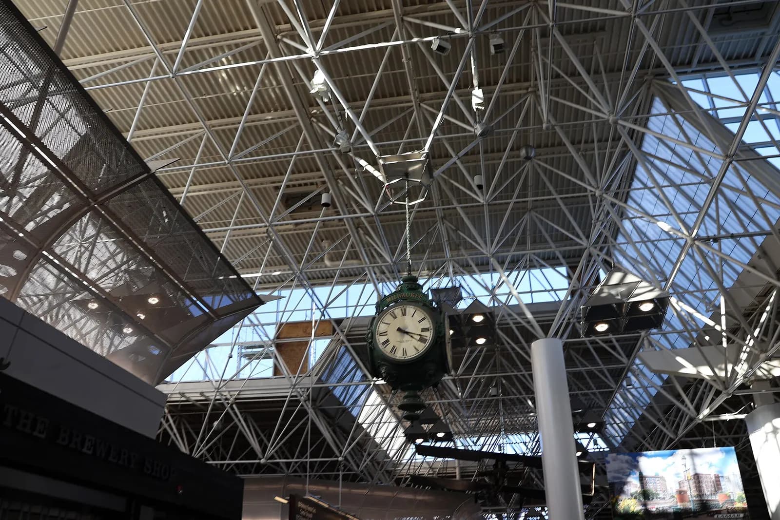 Hanging Milwaukee clock over the main terminal truss ceiling near The Brewery Shop.