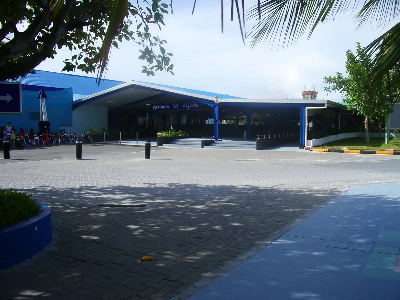 Arrivals entrance at Velana International Airport with blue roof canopy and control tower