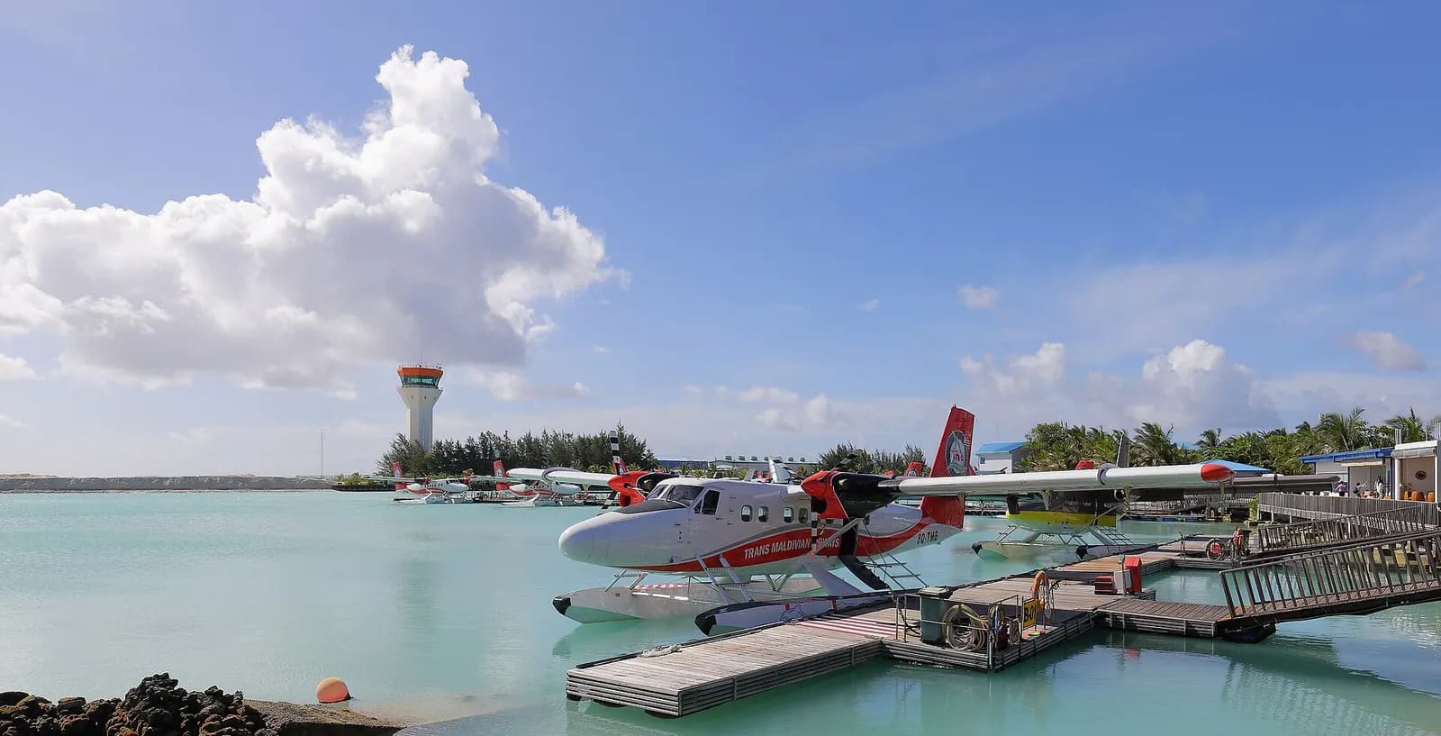 Trans Maldivian Airways DHC-6 Twin Otter seaplane docked at Velana with control tower behind
