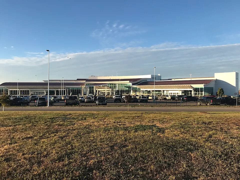 White passenger terminal and surface parking lot at Minot International Airport under a clear sky.