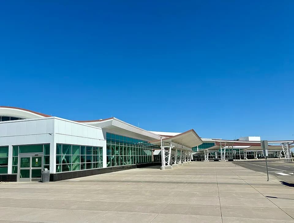 Empty curb and canopy at the Minot International Airport terminal entrance.