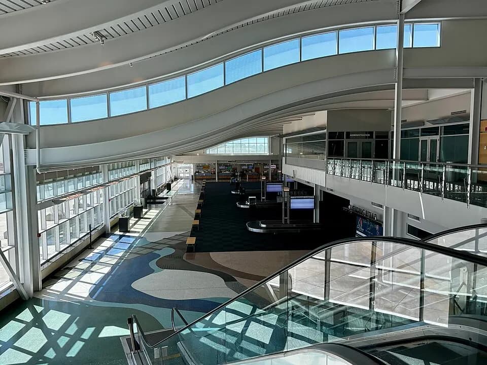 Two-level atrium at Minot International Airport with a patterned floor, escalator, and bag belt.