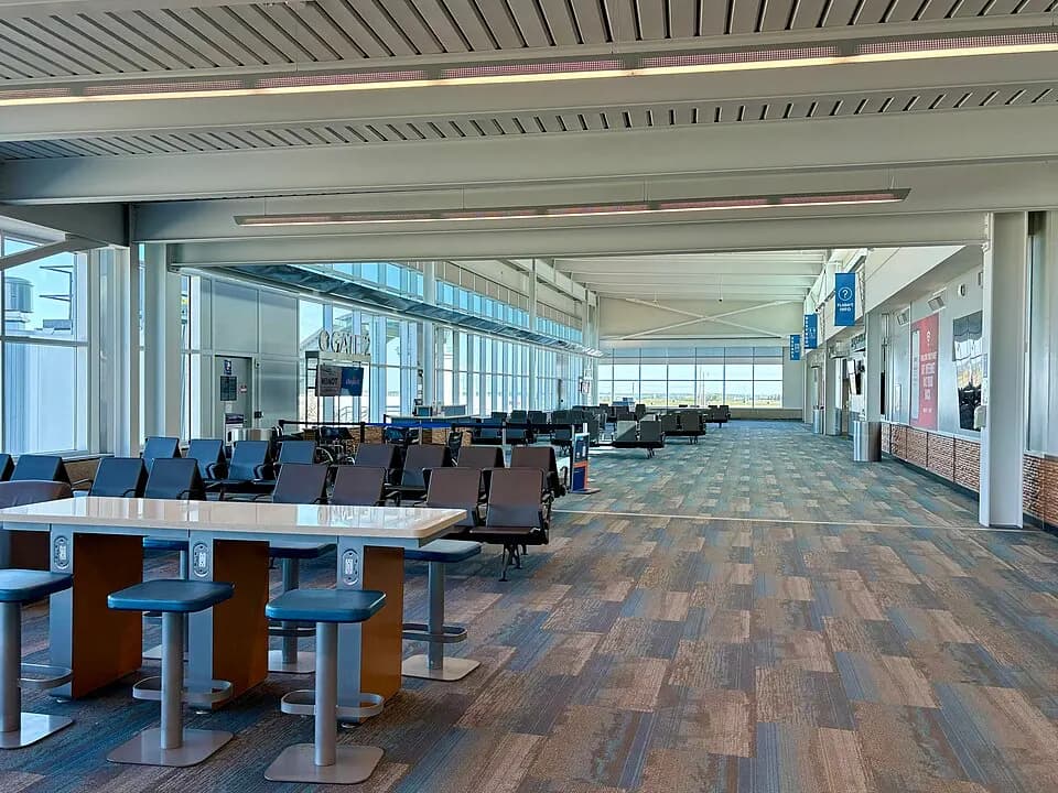 Gate holdroom seating, a work table, and windows at Minot International Airport.