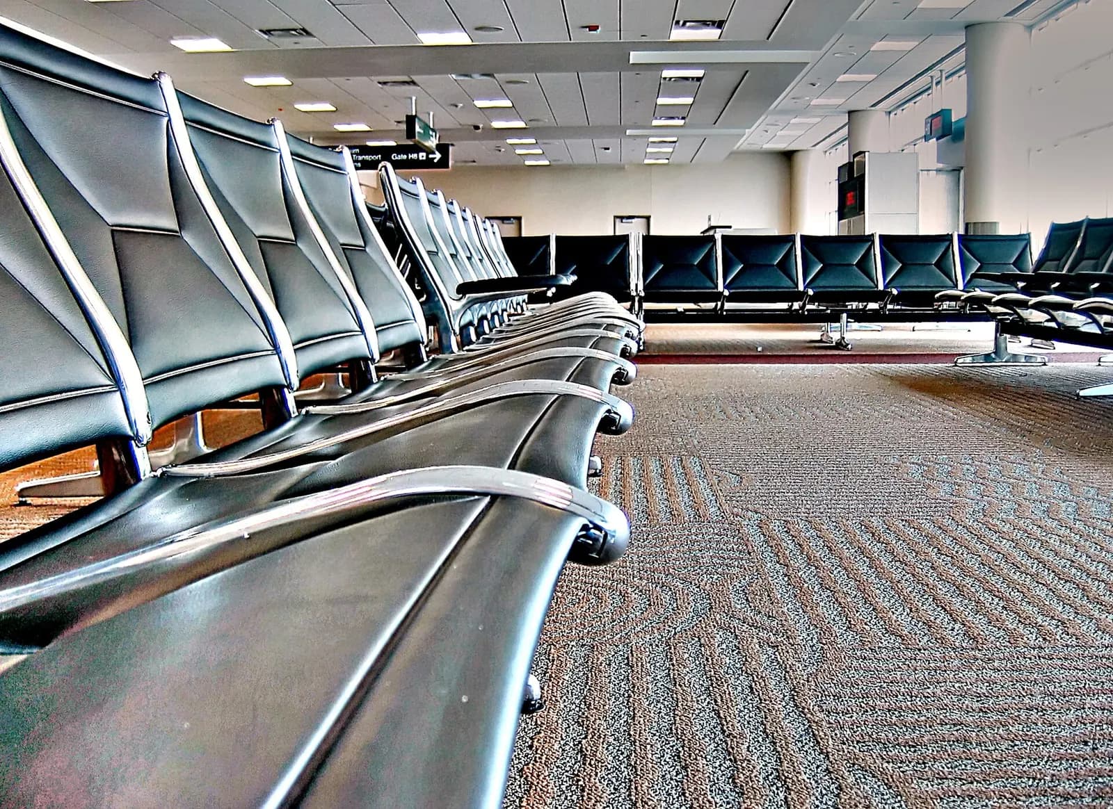 Empty gate seating rows with blue chairs and large windows in Terminal 2 at Minneapolis–Saint Paul International Airport.