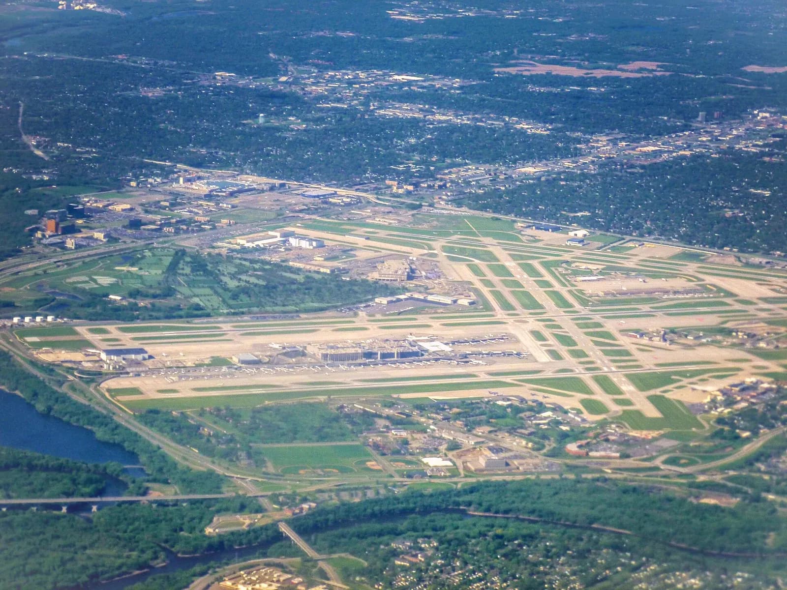 Aerial photograph looking down on Minneapolis–Saint Paul International Airport showing multiple parallel runways, terminals, and surrounding roads and greenery.
