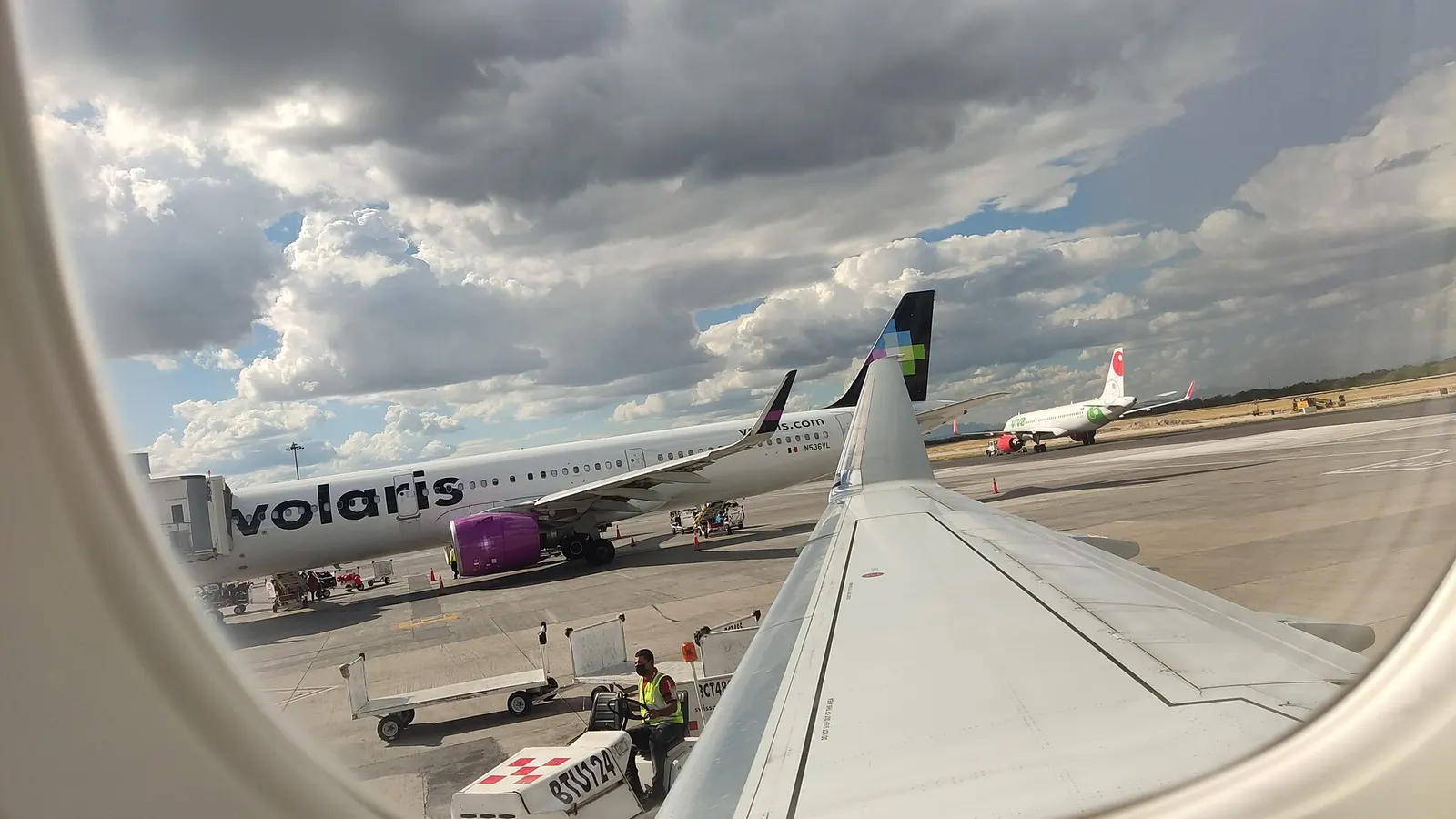 vista desde ventana de aeronave ERJ-170 (N212NN) de American Eagle a lado aire en sala A, MTY. Se observa un A320 neo de Volaris (N536VL) y un A320 neo de Viva Aerobus.