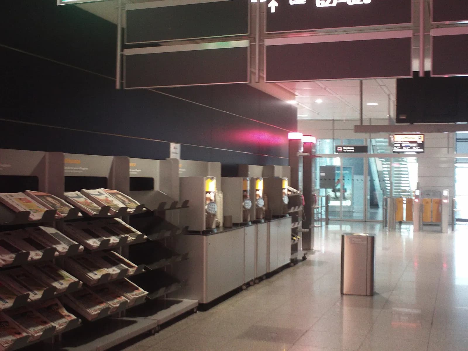 A self-service station in Terminal 2 offers free coffee dispensers and stacked daily newspapers for passengers.