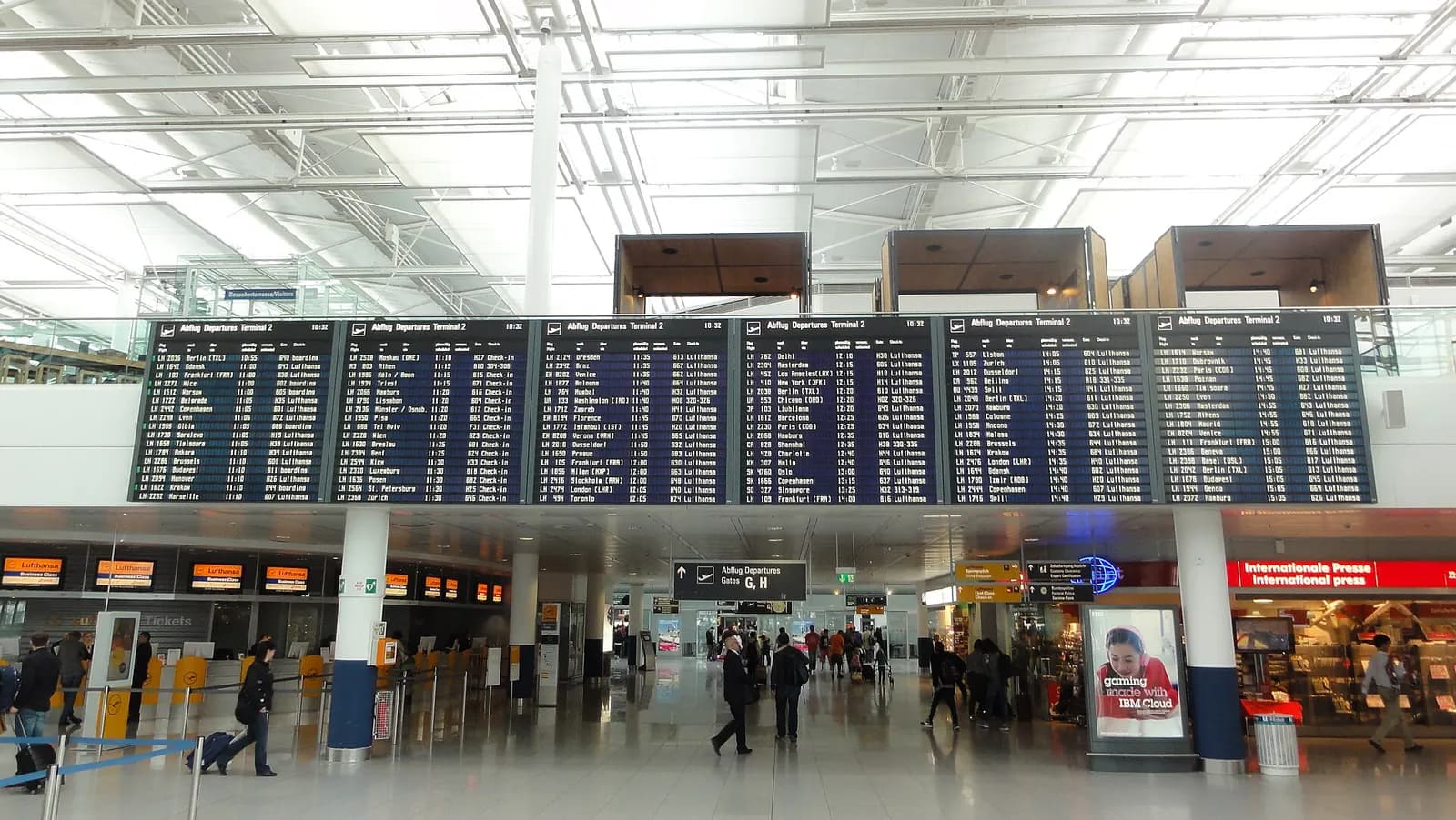 The main hall of Terminal 2 features tall windows, a high ceiling, and large electronic departure boards listing upcoming flights, gates, and boarding status.