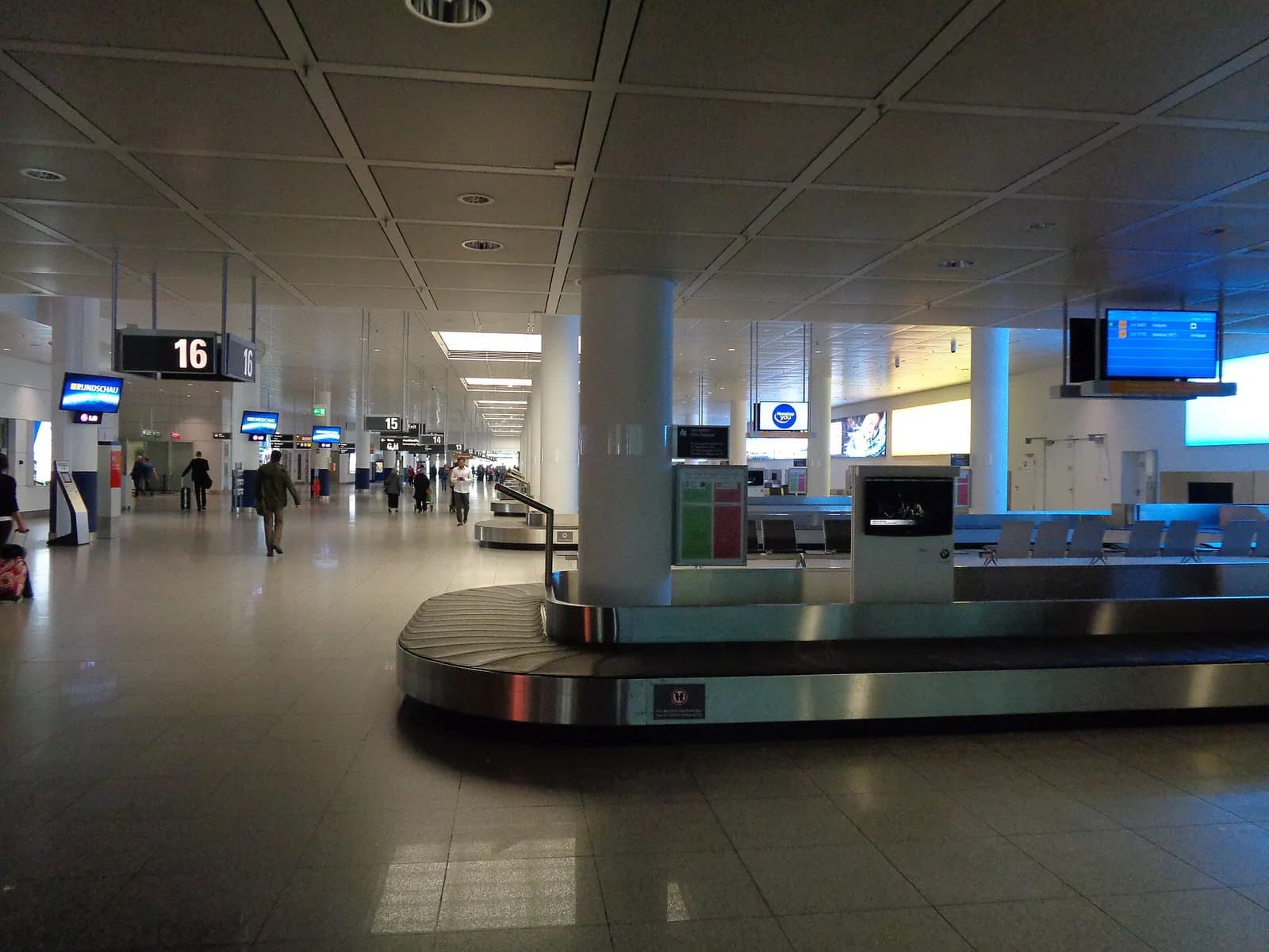 Multiple baggage carousels in a spacious arrivals hall at Terminal 2, with overhead signs marking each belt.